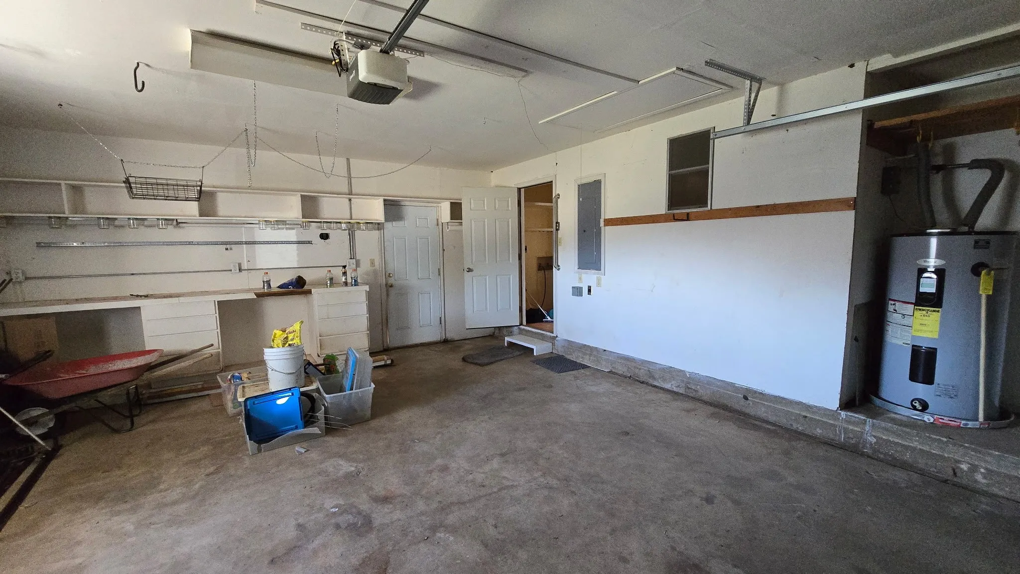 Attached two-car garage featuring a concrete floor, built-in shelving, and a water heater