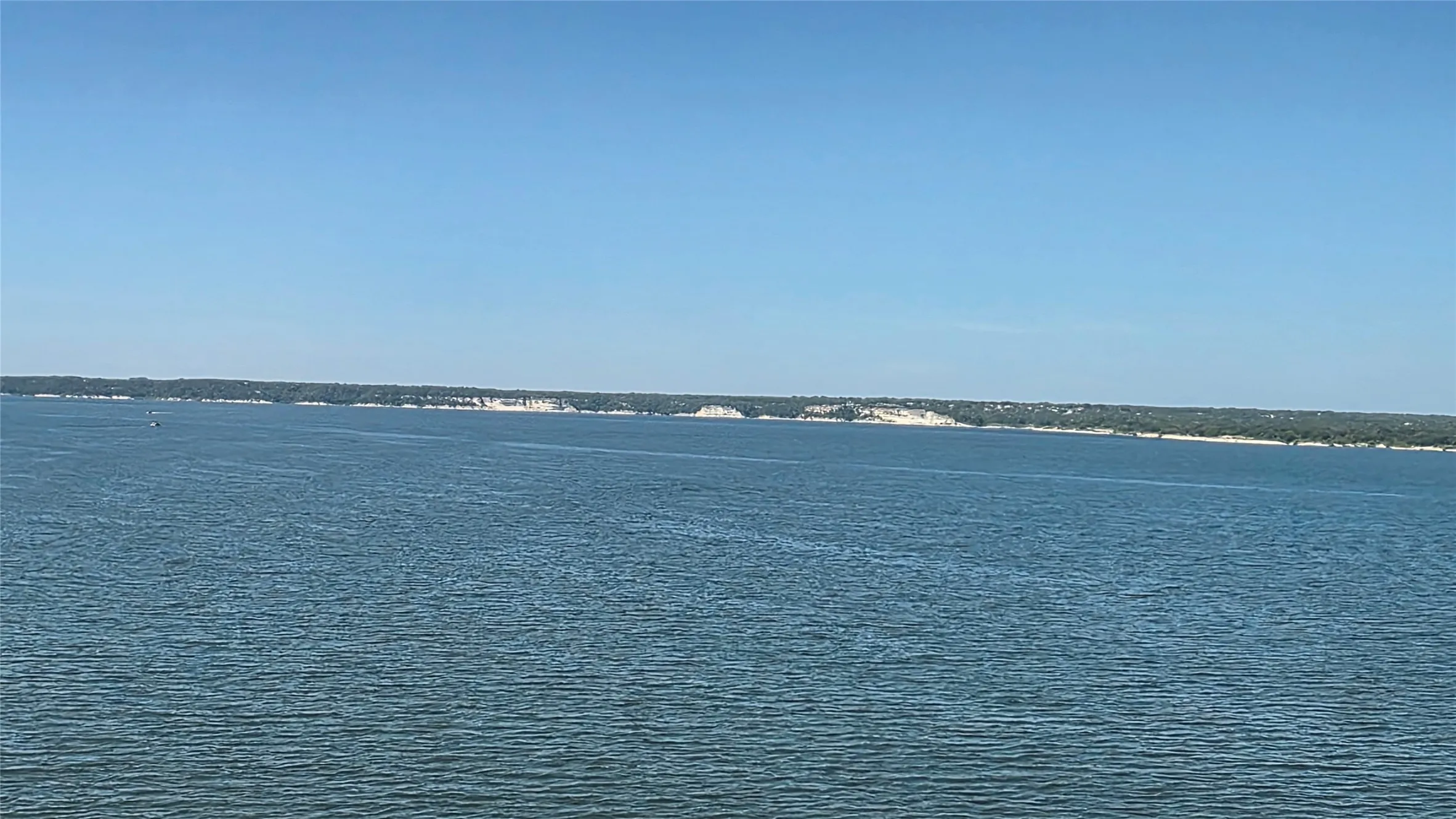Expansive open water with a distant treeline and natural shoreline