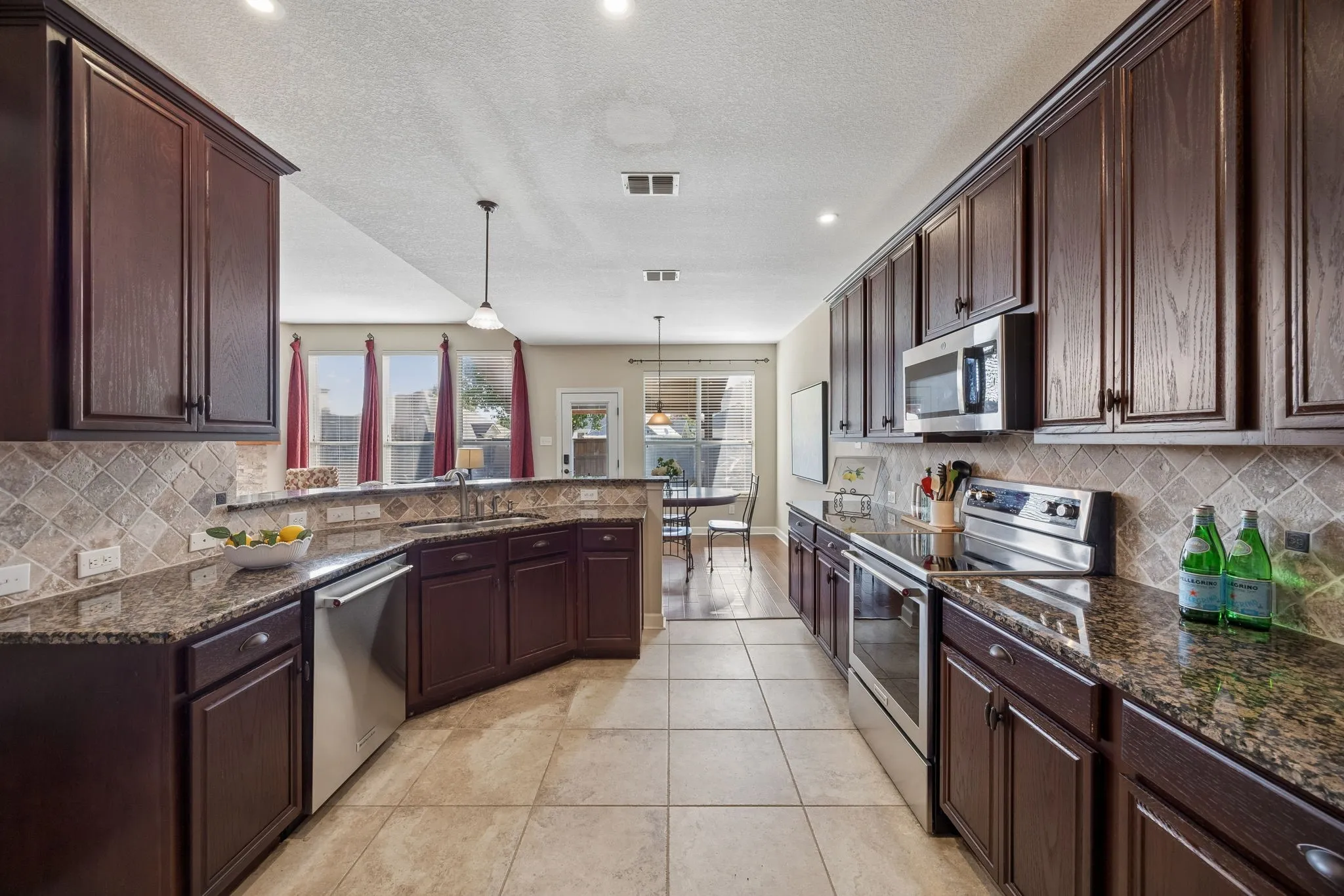 The kitchen includes an undermount stainless-steel sink, backsplash and recessed lighting.