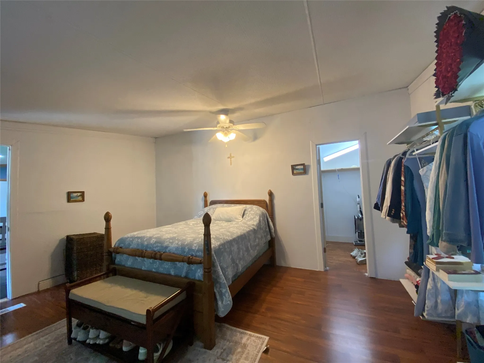 Bedroom featuring dark wood-style floors, a spacious closet, and a ceiling fan