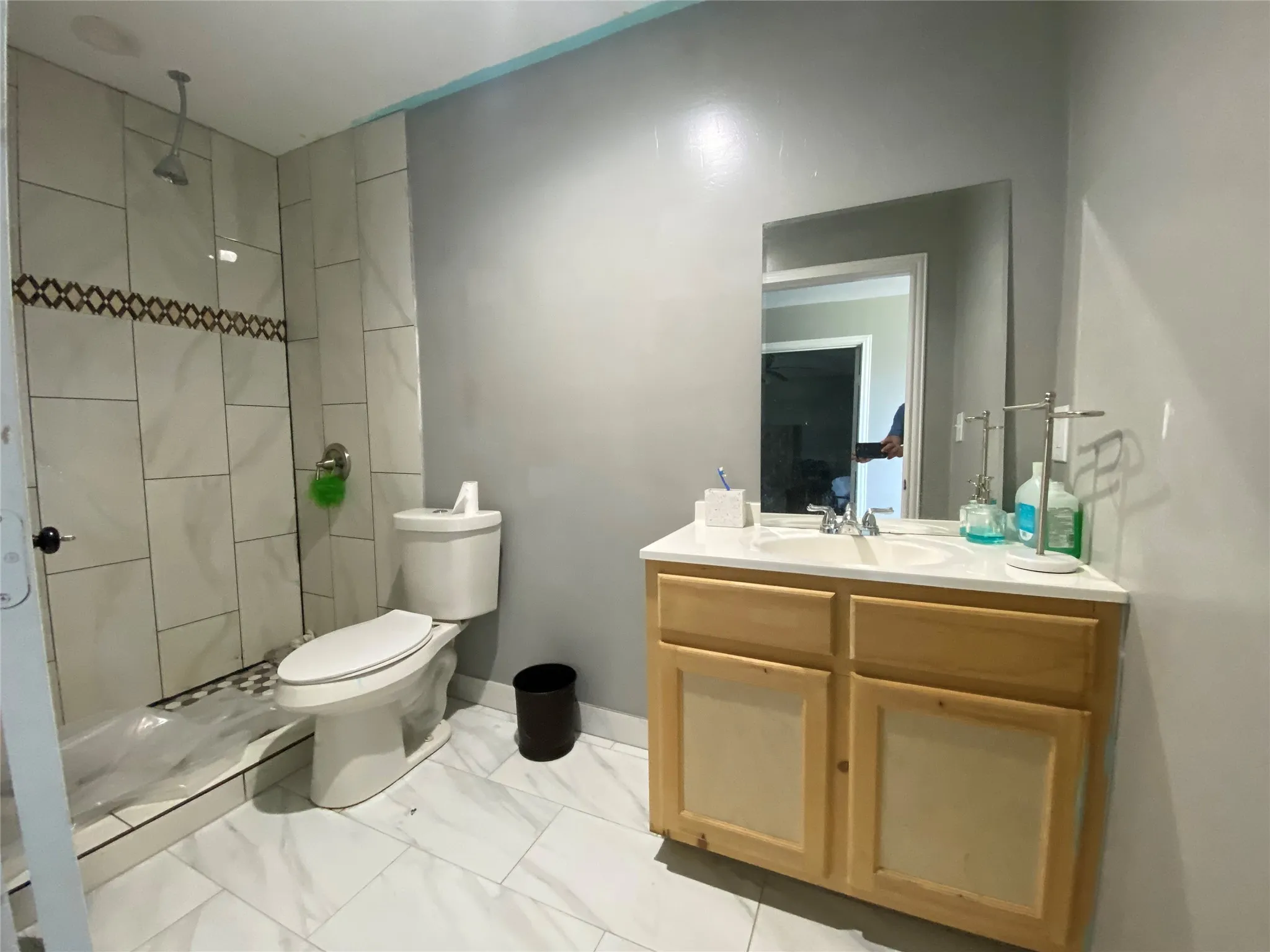 Bathroom featuring vanity, a tile shower, and light marble finish flooring