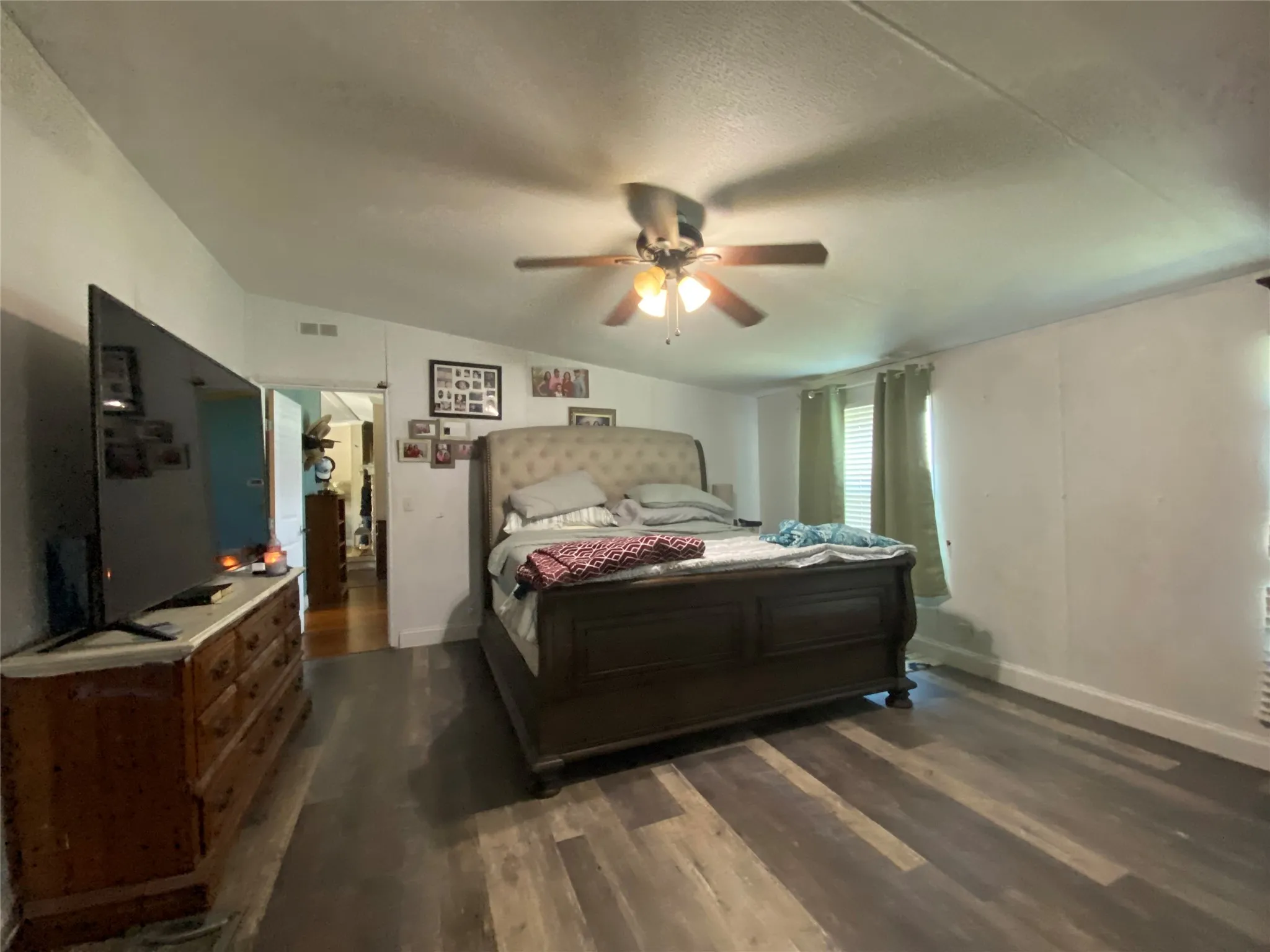 Bedroom with dark wood-type flooring, ceiling fan, vaulted ceiling, and a textured ceiling