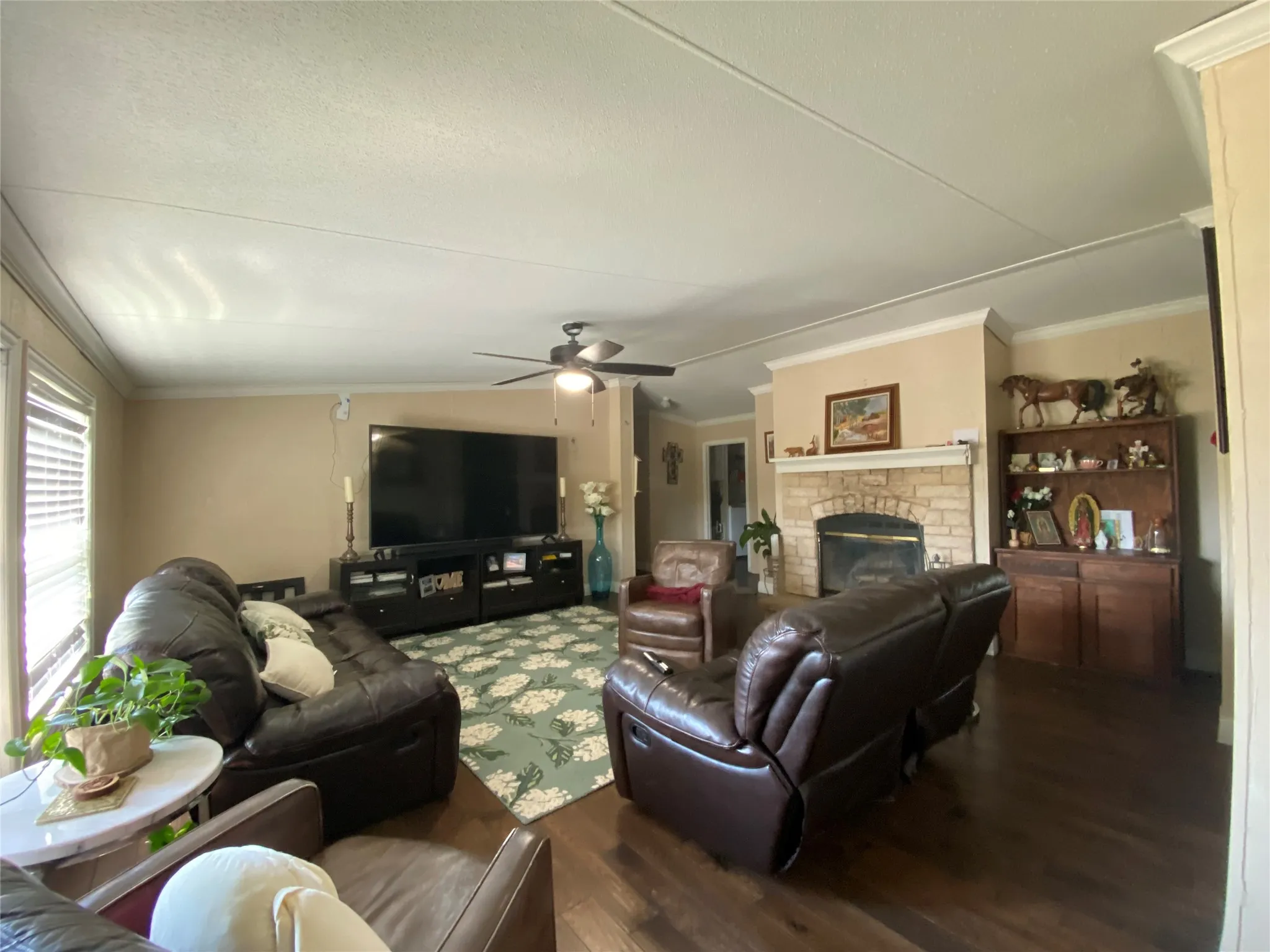Living room featuring ornamental molding, wood finished floors, a brick fireplace, and a ceiling fan