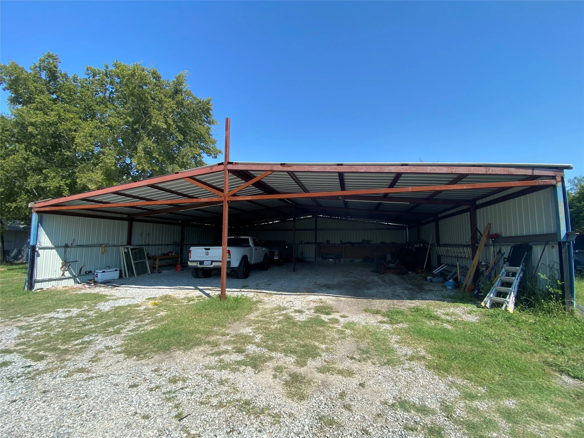 View of parking / parking lot with driveway, a pole building, and a carport