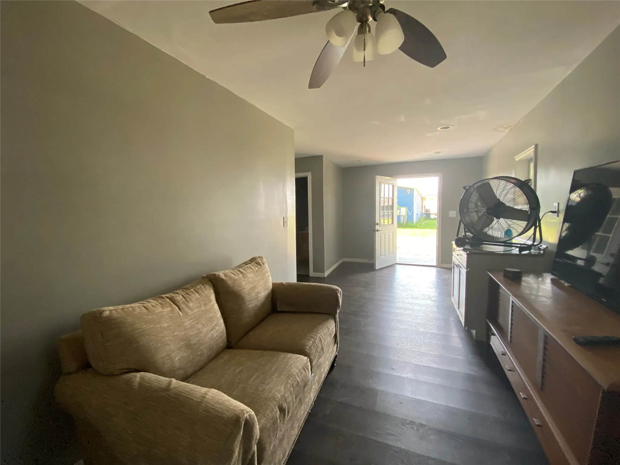 Living room featuring dark wood-type flooring and ceiling fan