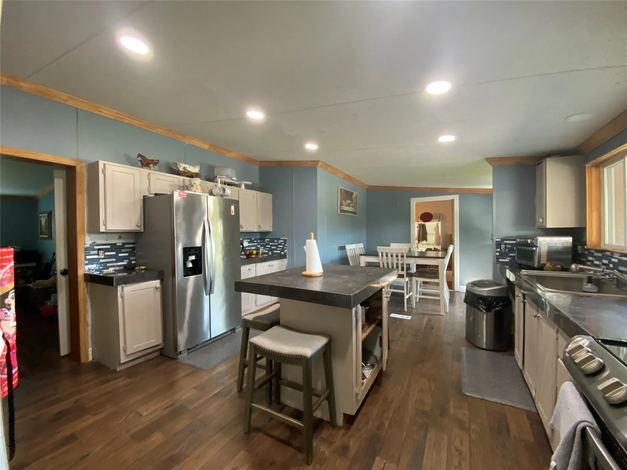 Kitchen featuring backsplash, dark countertops, a breakfast bar area, a center island, and stainless steel appliances