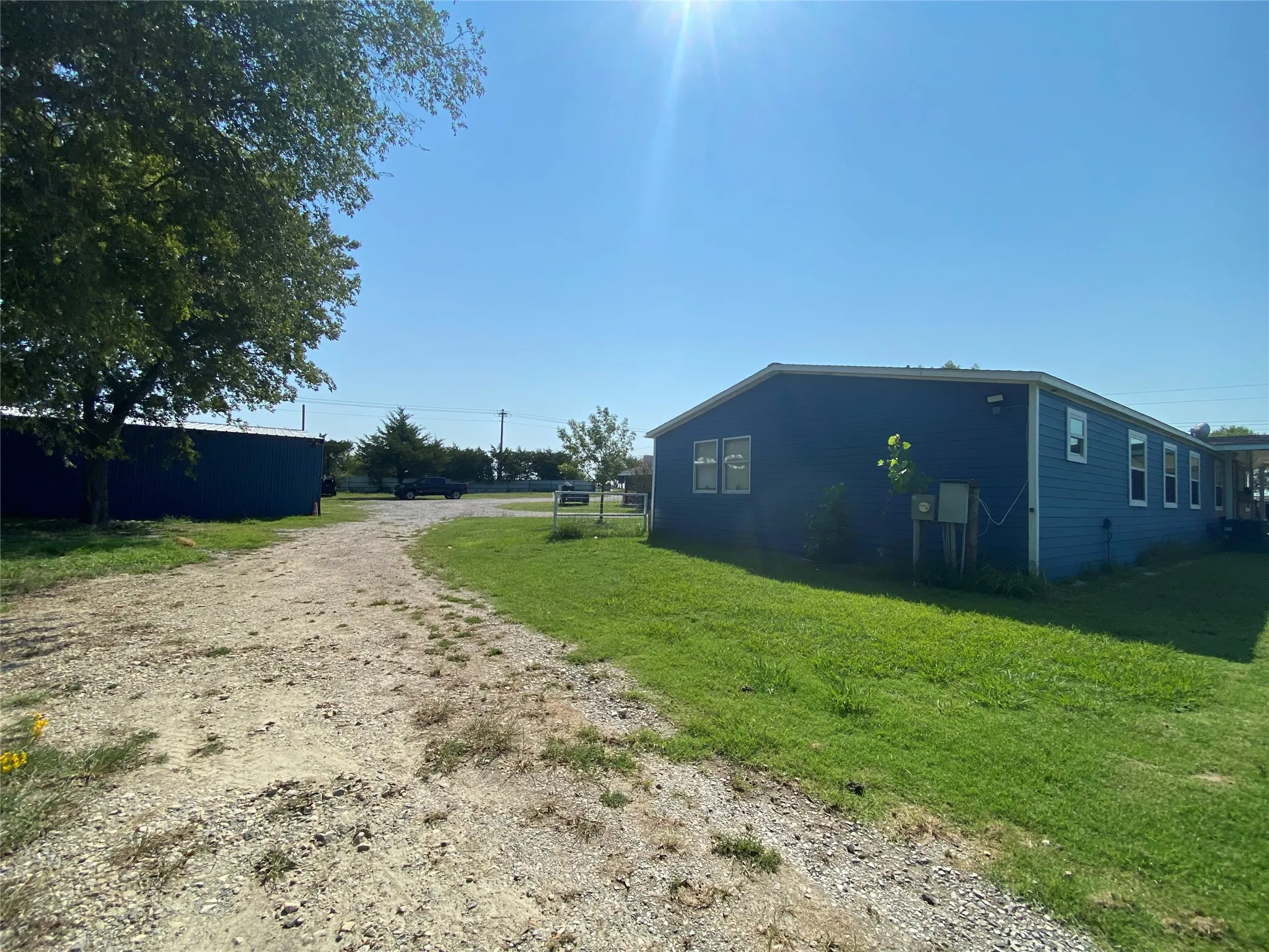 View of side of property with dirt driveway and a yard