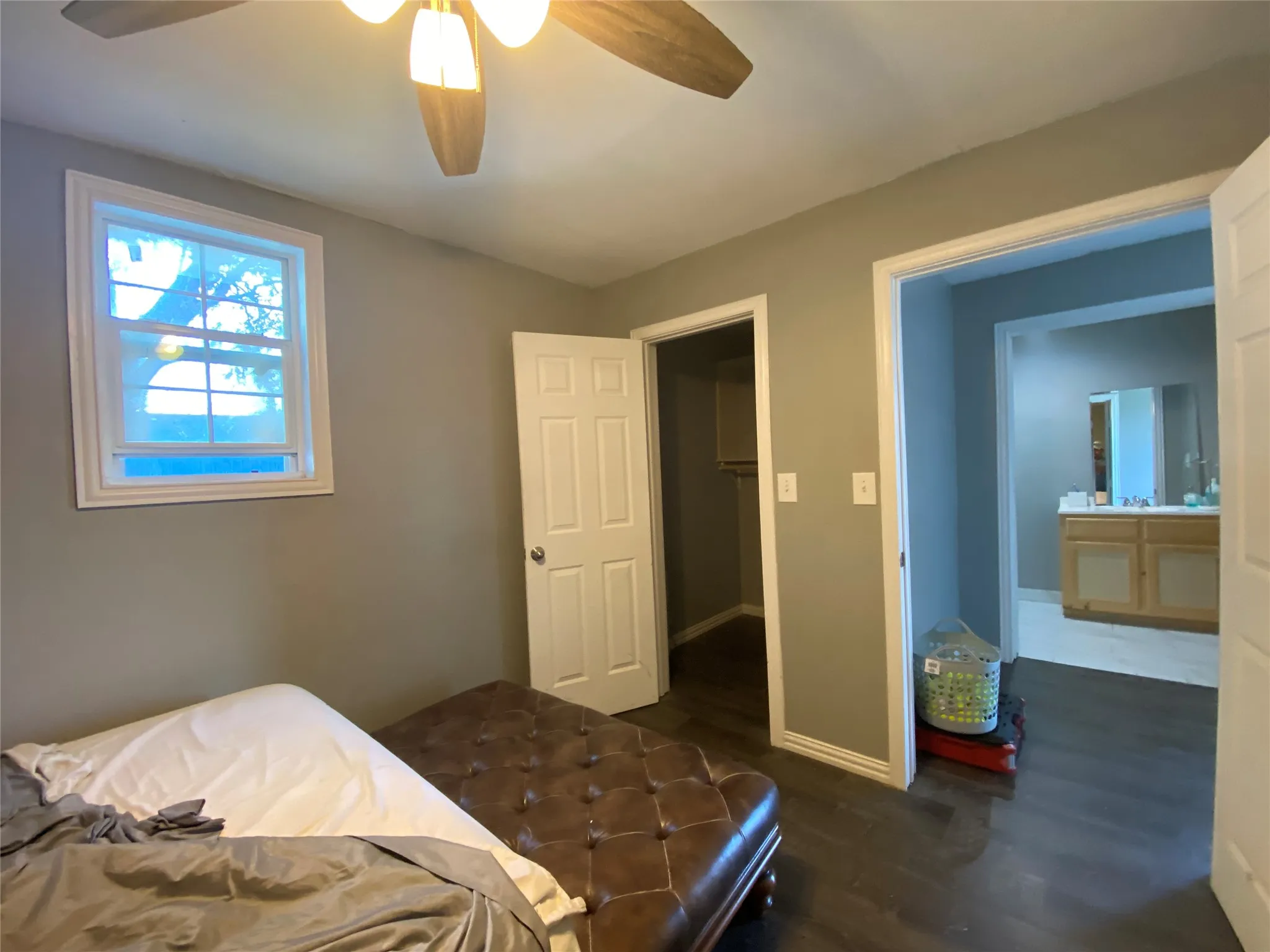 Bedroom with dark wood-style floors, a spacious closet, and a ceiling fan