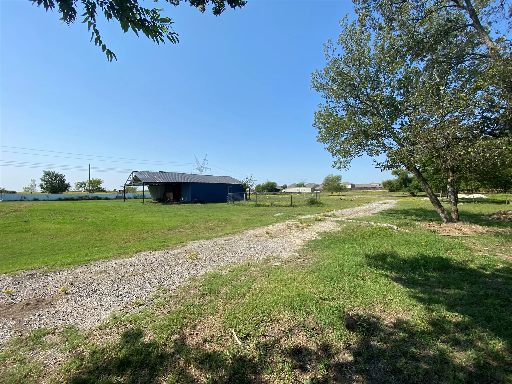 View of dirt / gravel road featuring a view of rural / pastoral area and an outbuilding