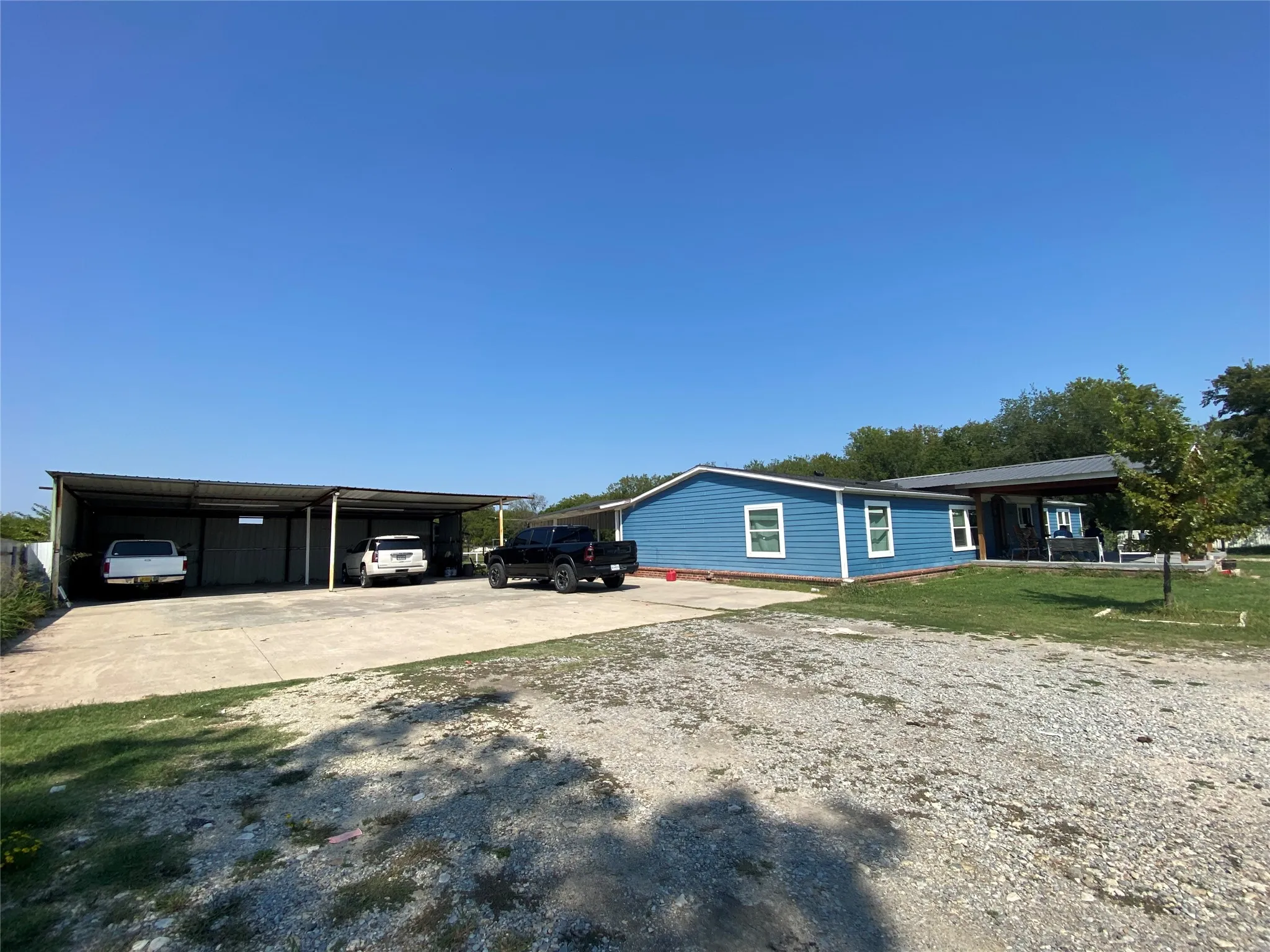 View of side of property featuring driveway, a carport, and a yard