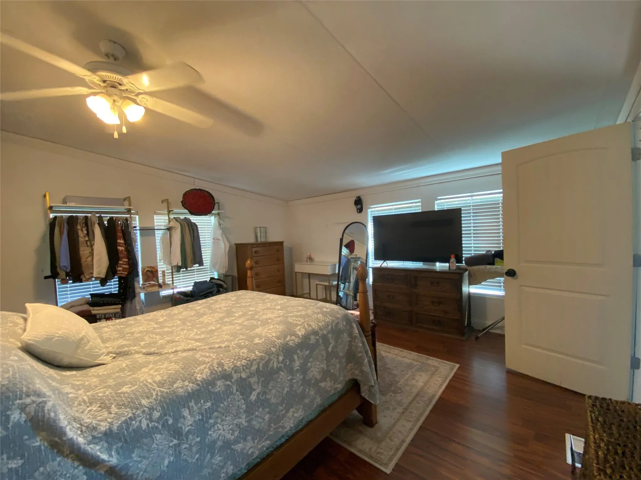 Bedroom with dark wood-style floors, ceiling fan, and ornamental molding