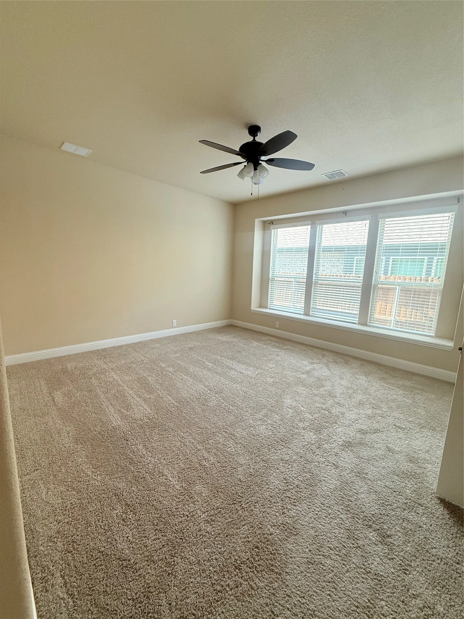Spacious room featuring neutral-toned carpeting and light-colored walls