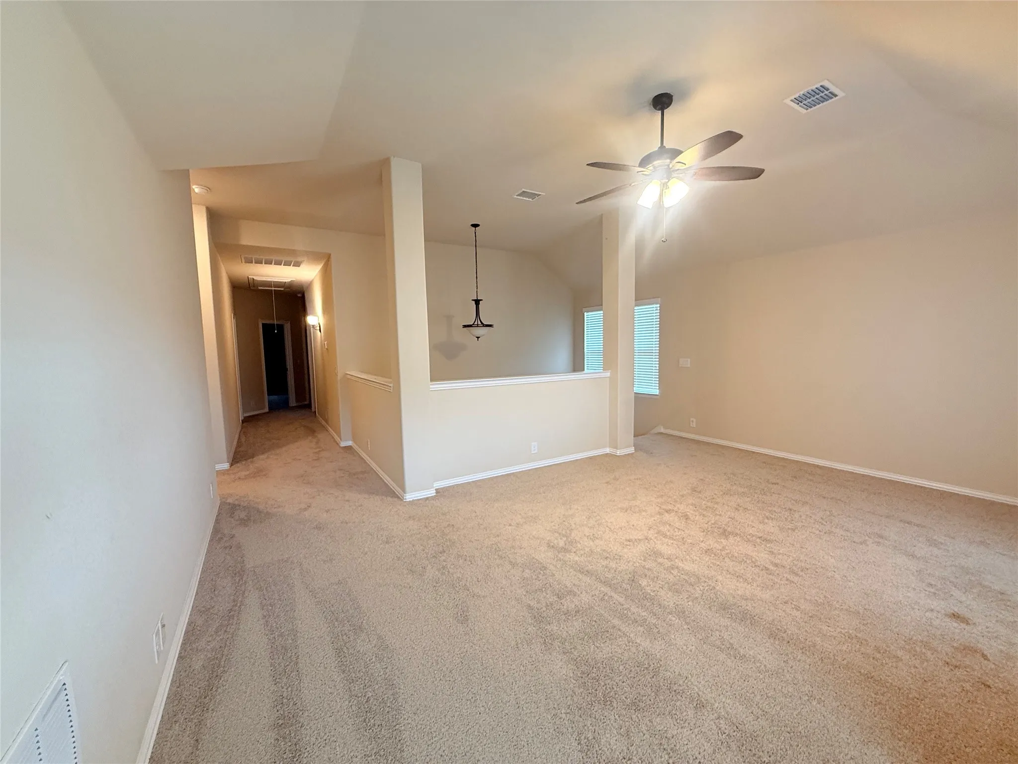 Expansive carpeted area featuring a ceiling fan, recessed lighting, and natural light from visible windows