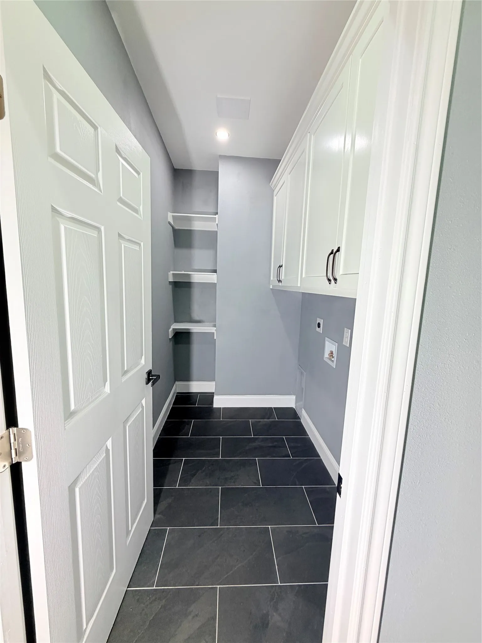 Utility room featuring dark rectangular floor tiles and light gray walls