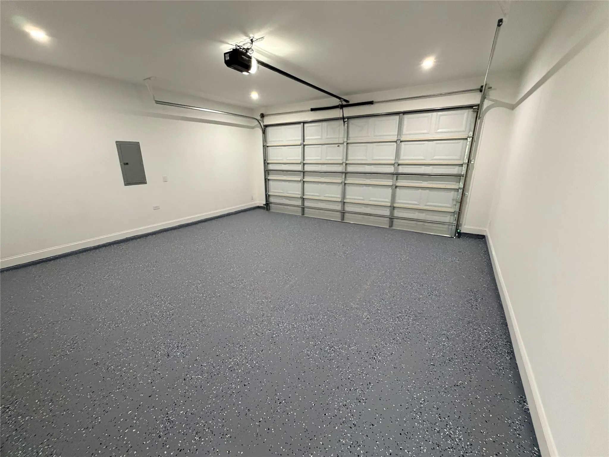 Spacious garage featuring a durable epoxy speckled floor, recessed lighting, white walls, and an automatic garage door opener