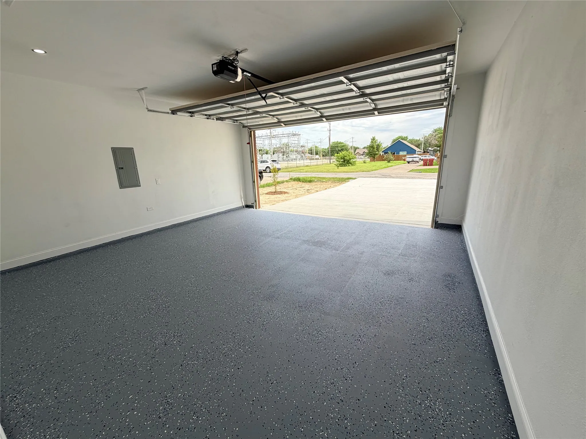 Attached garage featuring a gray epoxy-coated floor, white painted walls, recessed lighting, and an automatic garage door opener