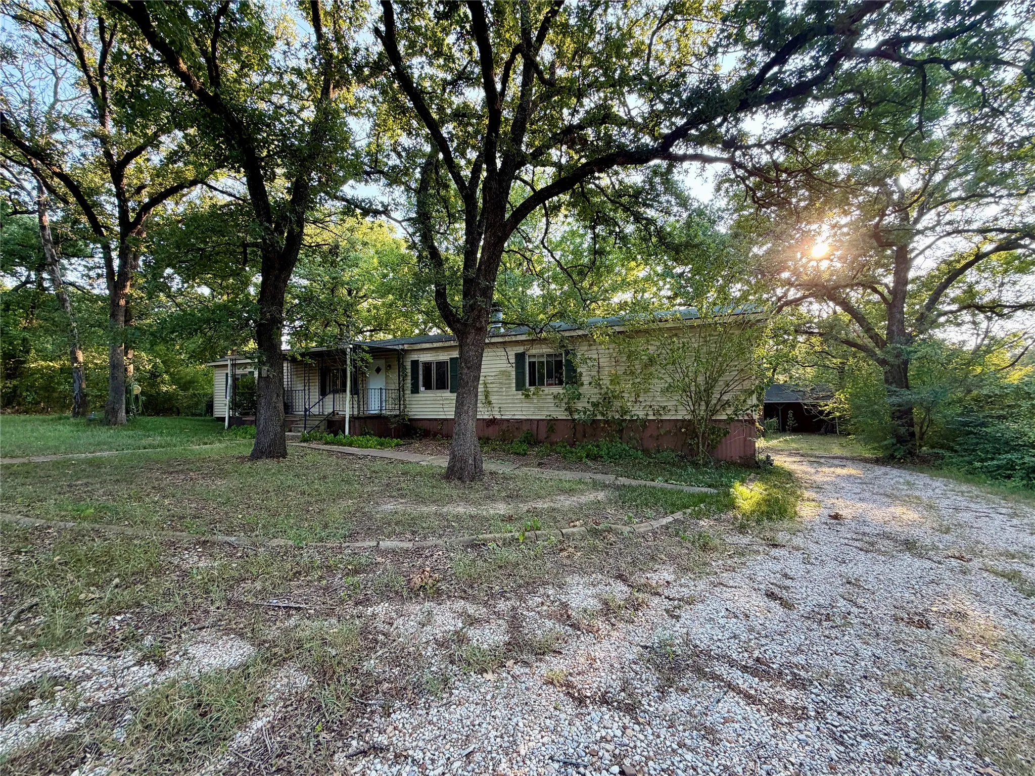 Single-story residence featuring light-colored siding, a ample covered entry porch, and a gravel driveway