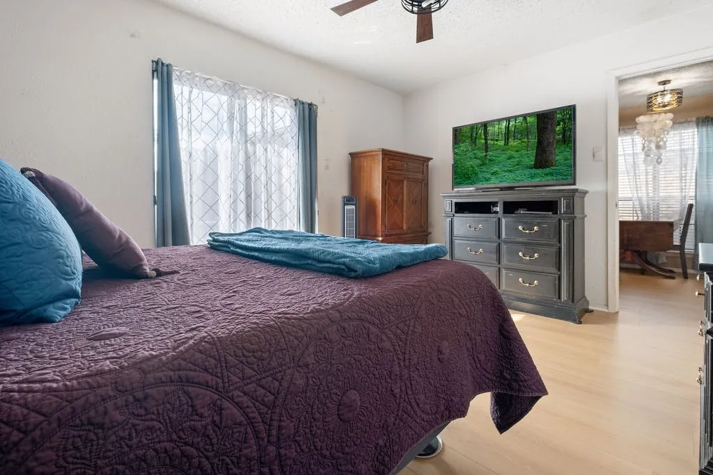 Light-toned wood-finish flooring extends throughout this room, featuring a window with sheer and blackout curtains