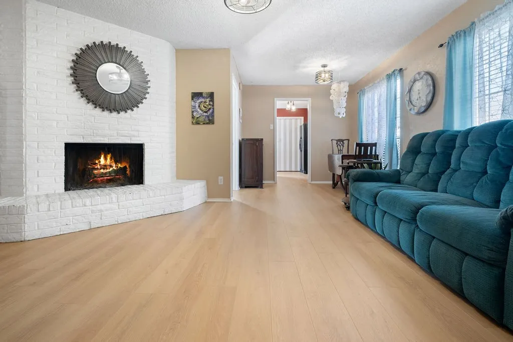 Living area featuring a painted brick fireplace, light wood-finish flooring, and recessed lighting