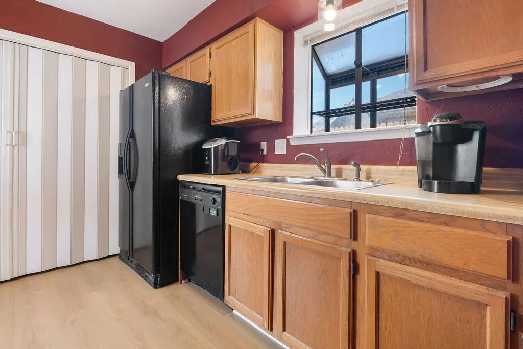 Warm burgundy walls frame this updated kitchen featuring wood-finish cabinetry, black stainless steel appliances, and wood-finish countertops