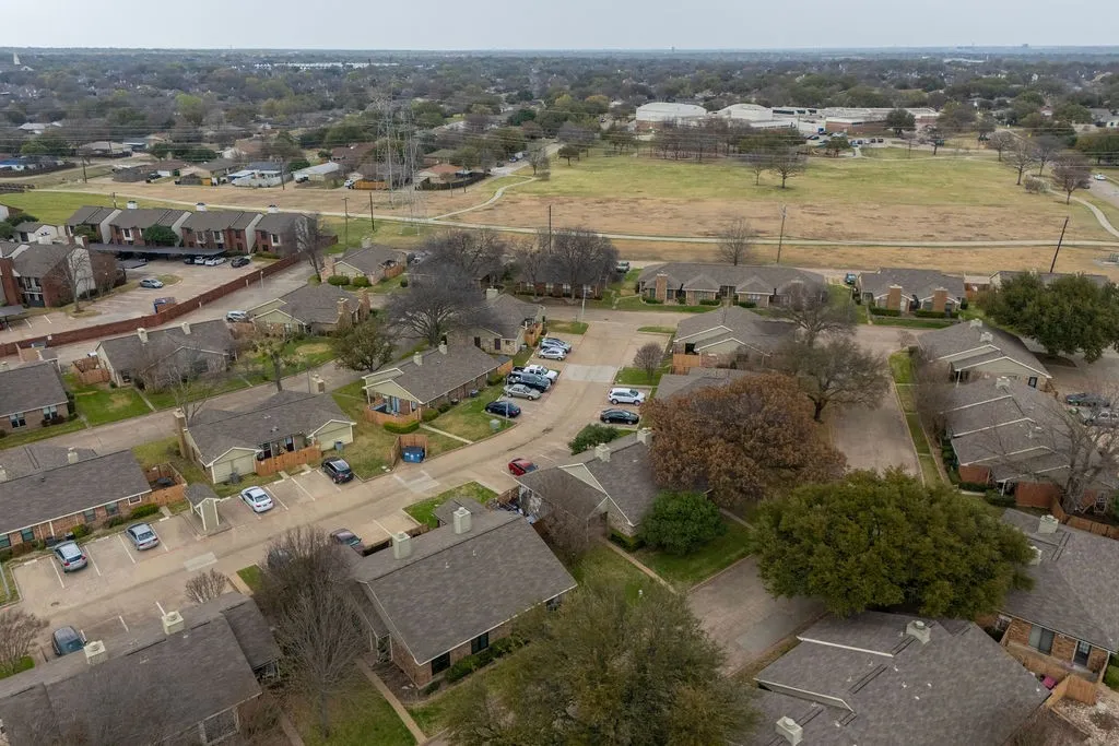 Residential community with a mix of single-story and multi-story structures, featuring paved parking areas and mature landscaping