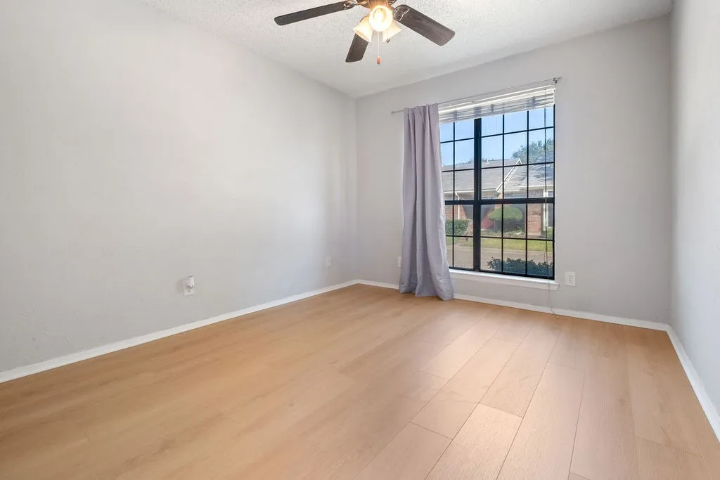 Room featuring light wood-finish flooring, a multi-pane window, and a ceiling fan with integrated lighting