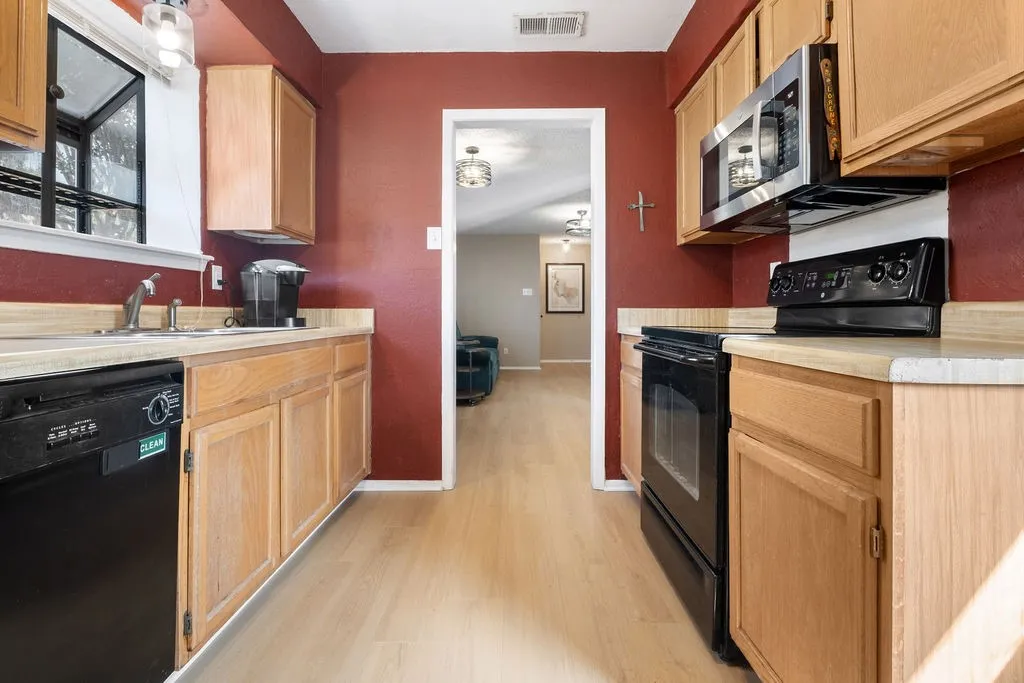 Galley kitchen with light wood-finish cabinetry, light wood-finish flooring, and light countertops