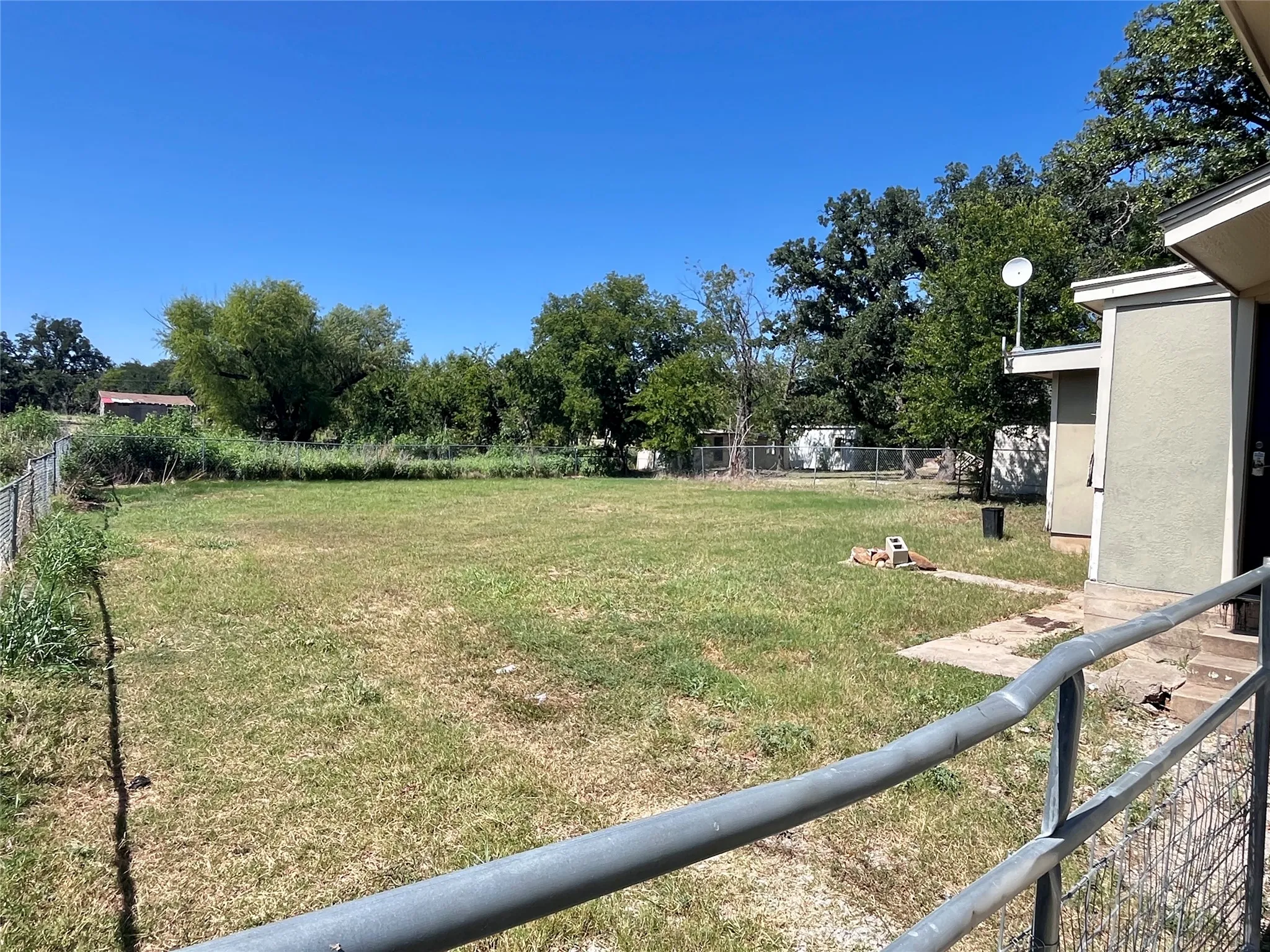 Deep, fenced backyard surrounded by mature trees, offering plenty of room for gardening, entertaining, pets, or simply enjoying the outdoors. Oversized gate allows vehicle access to rear if needed.