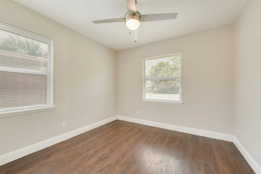Room featuring wood-finish flooring, neutral wall tones, and white baseboards