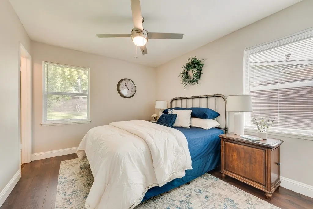 Bedroom featuring wood-finish flooring, two windows, and a ceiling fan with integrated lighting