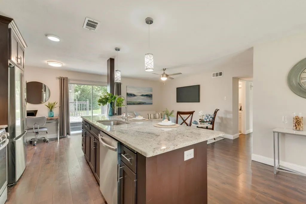 Kitchen island with a light-toned countertop, integrated sink, and stainless steel dishwasher