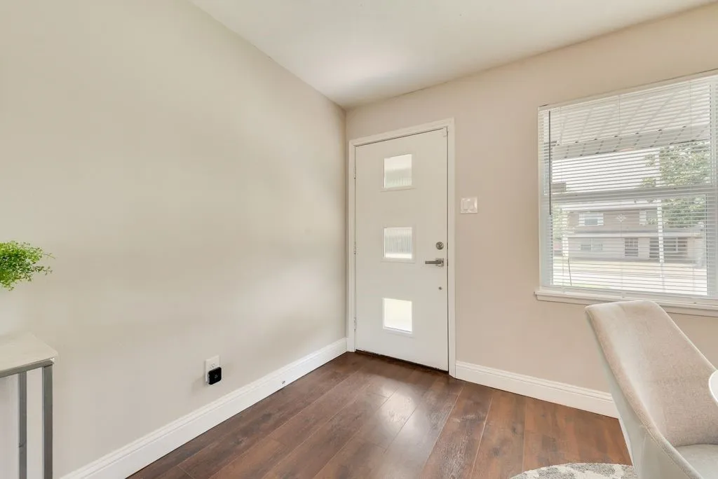 Entryway featuring a contemporary white door with three frosted glass inserts, dark wood-finish flooring, white baseboards, and neutral wall paint