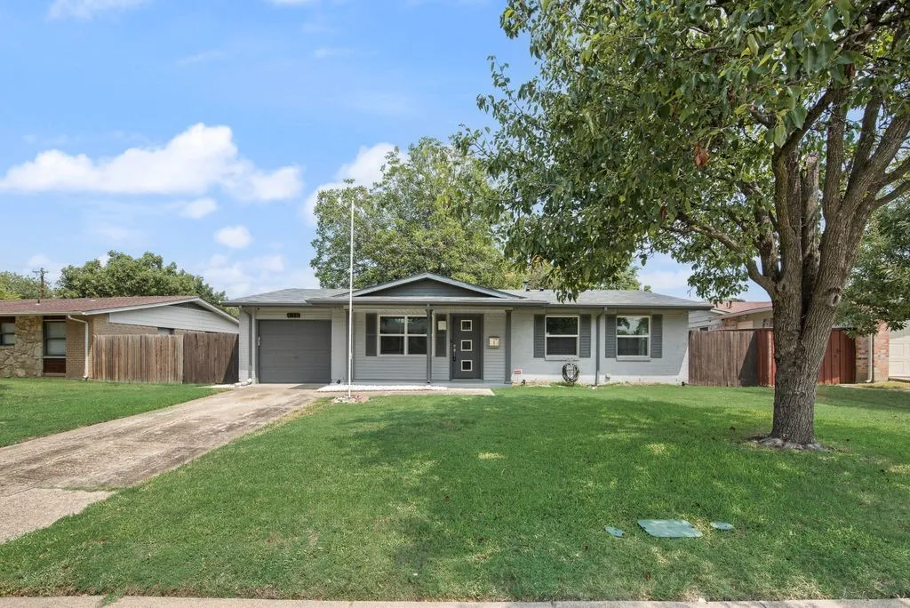 Single-story residence featuring a gray exterior, a front-facing garage, and a mature shade tree