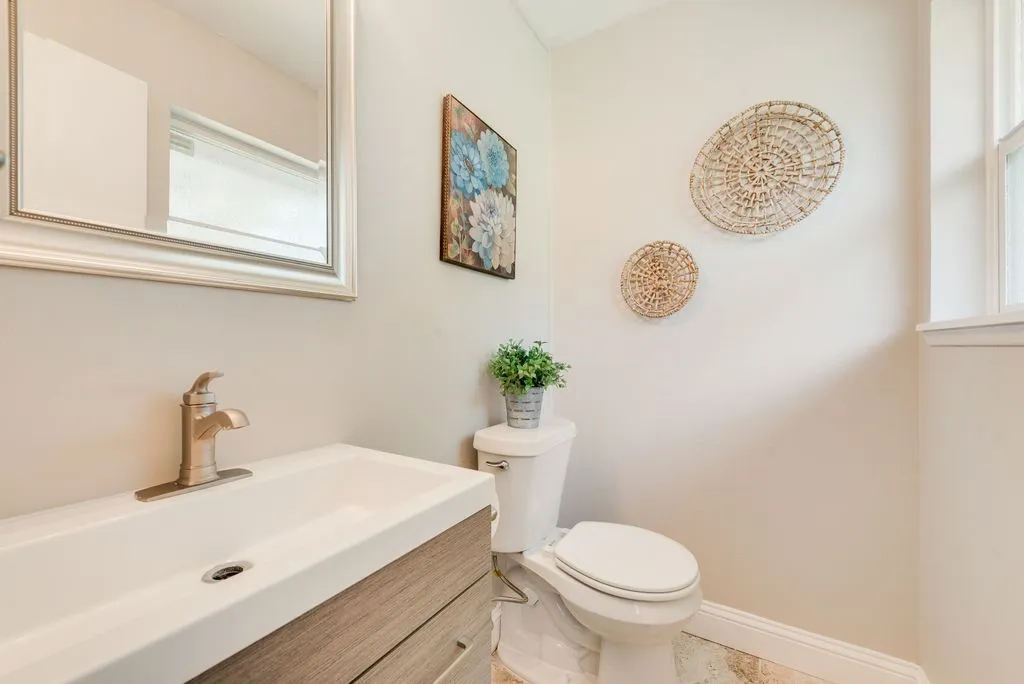 Contemporary vanity with integrated sink, brushed nickel faucet, framed mirror, and natural light from a window