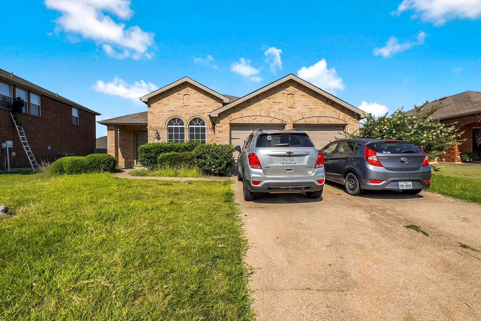 Brick exterior with arched window details, a two-car garage, and a concrete driveway