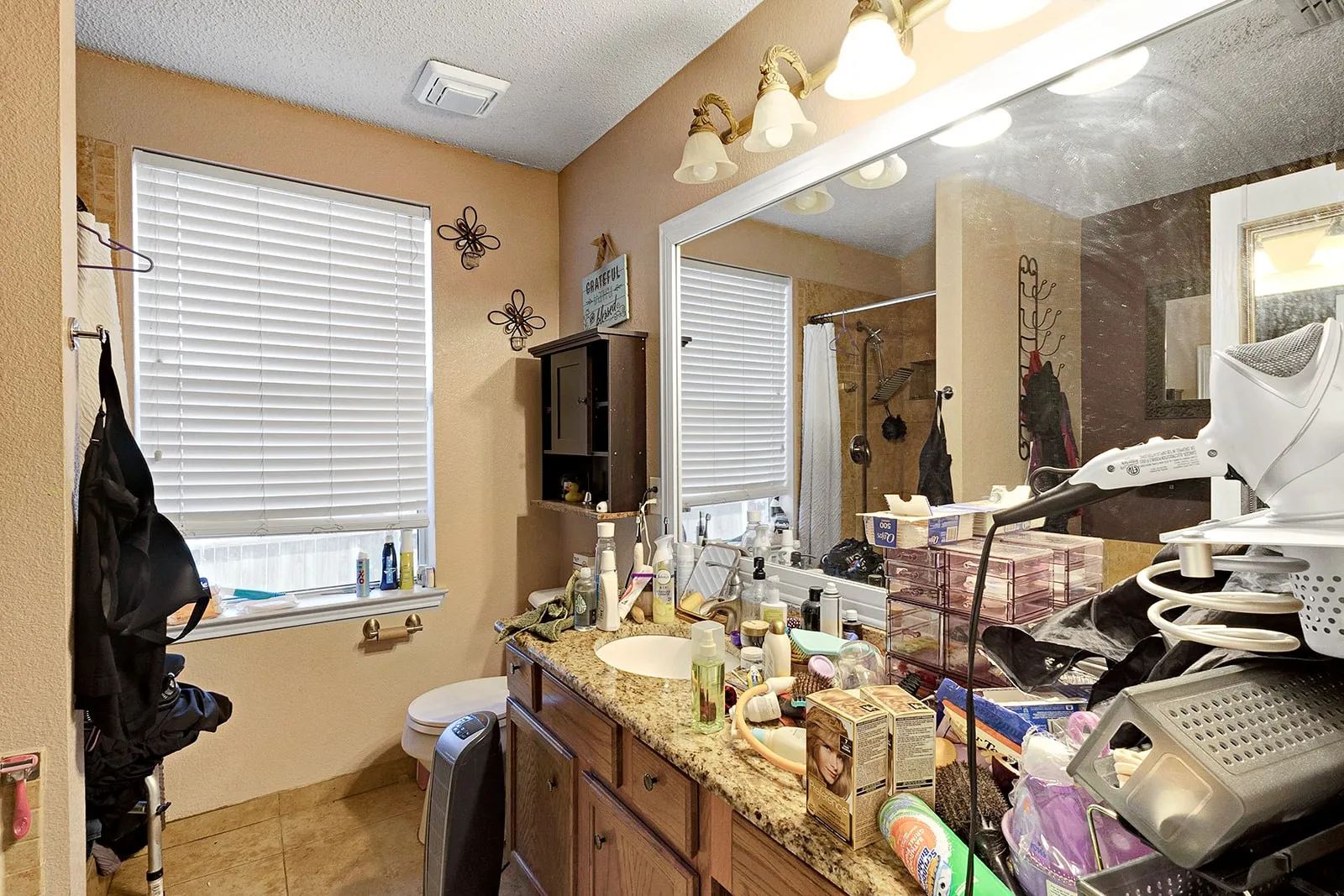 Bathroom featuring a granite-finish countertop, wood-finish cabinetry, built-in medicine cabinet, and a large vanity mirror with sconce lighting