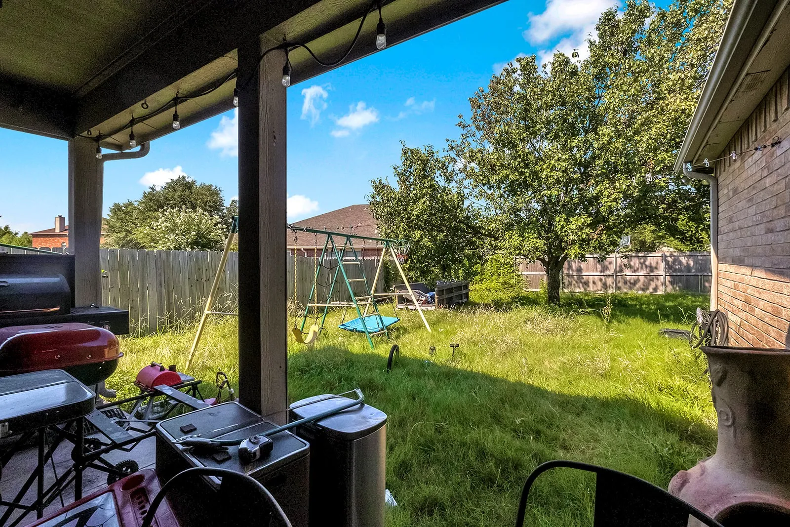 Covered patio area with string lights and a brick exterior wall