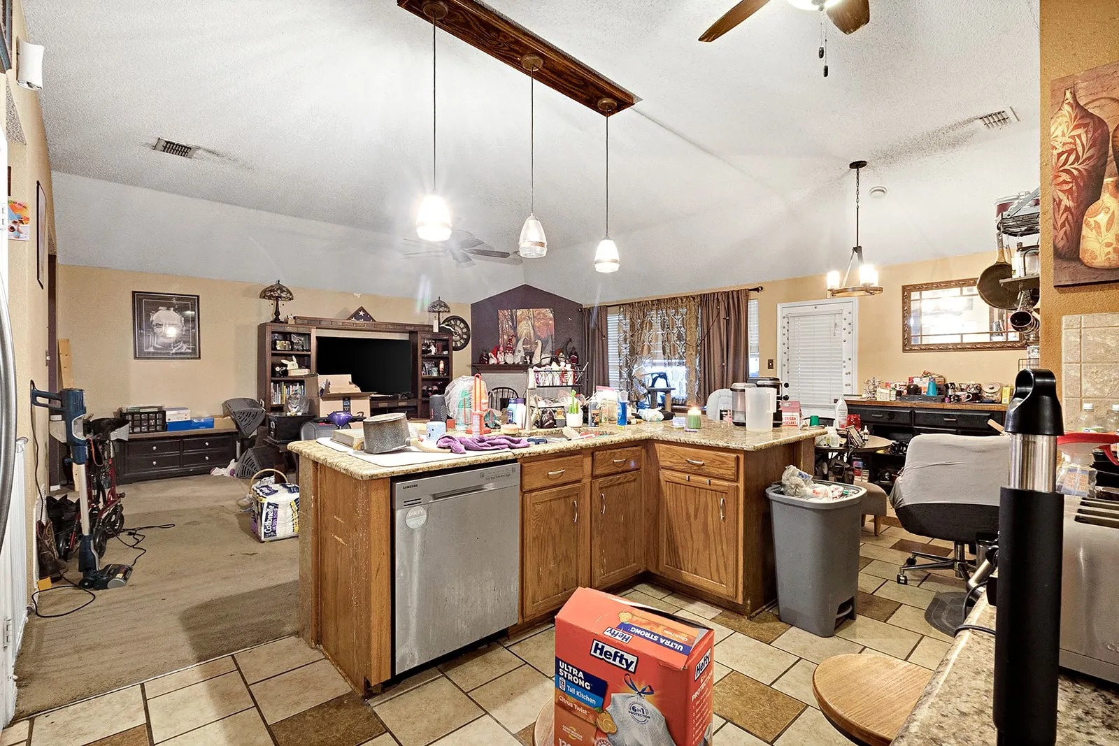 Open concept kitchen featuring tile flooring, wooden cabinetry, and a built-in dishwasher