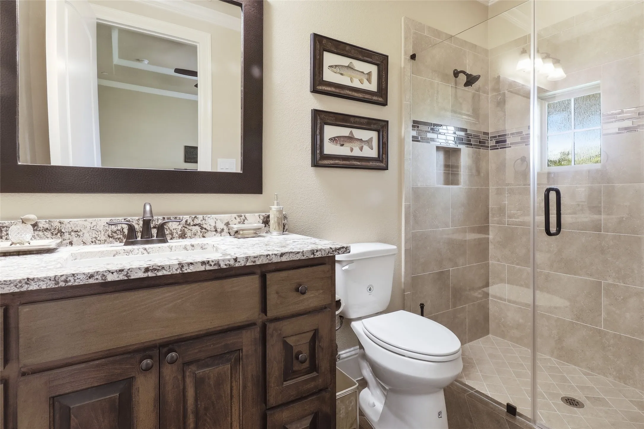 Full view of this bedroom's private bath with its glass beautiful glass enclosure and custom tilework.