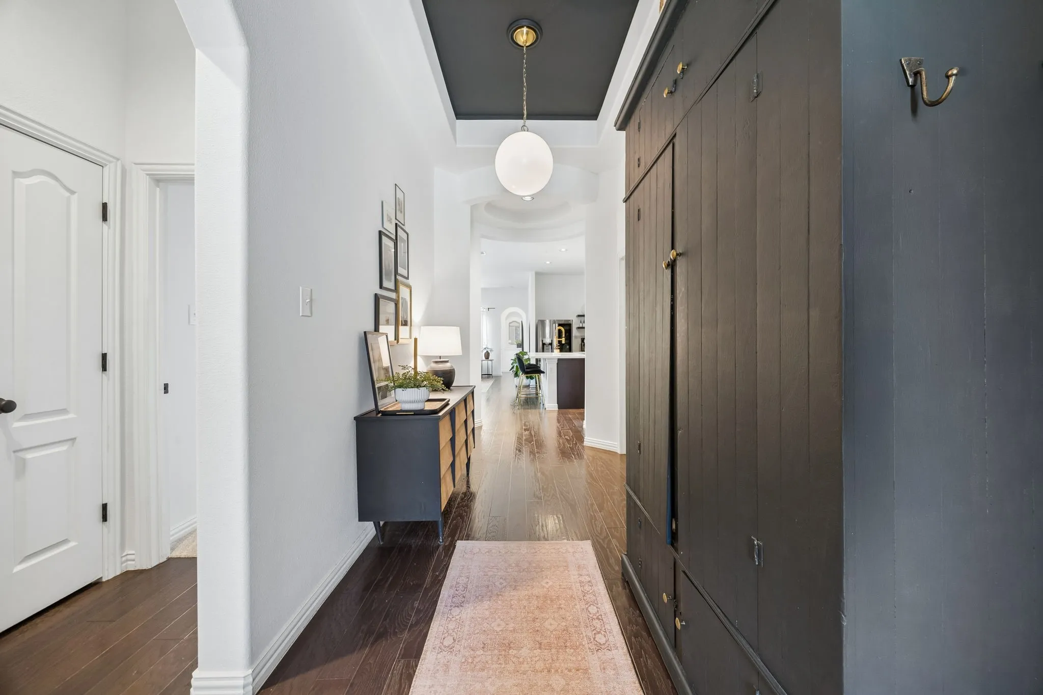 Entry is wide.   Picture is deceiving with large armoire for shoes on the right.    Beautiful custom lighting with decorative contrasting paint compliment the height of the ceilings.   2 bedrooms and bath to the left