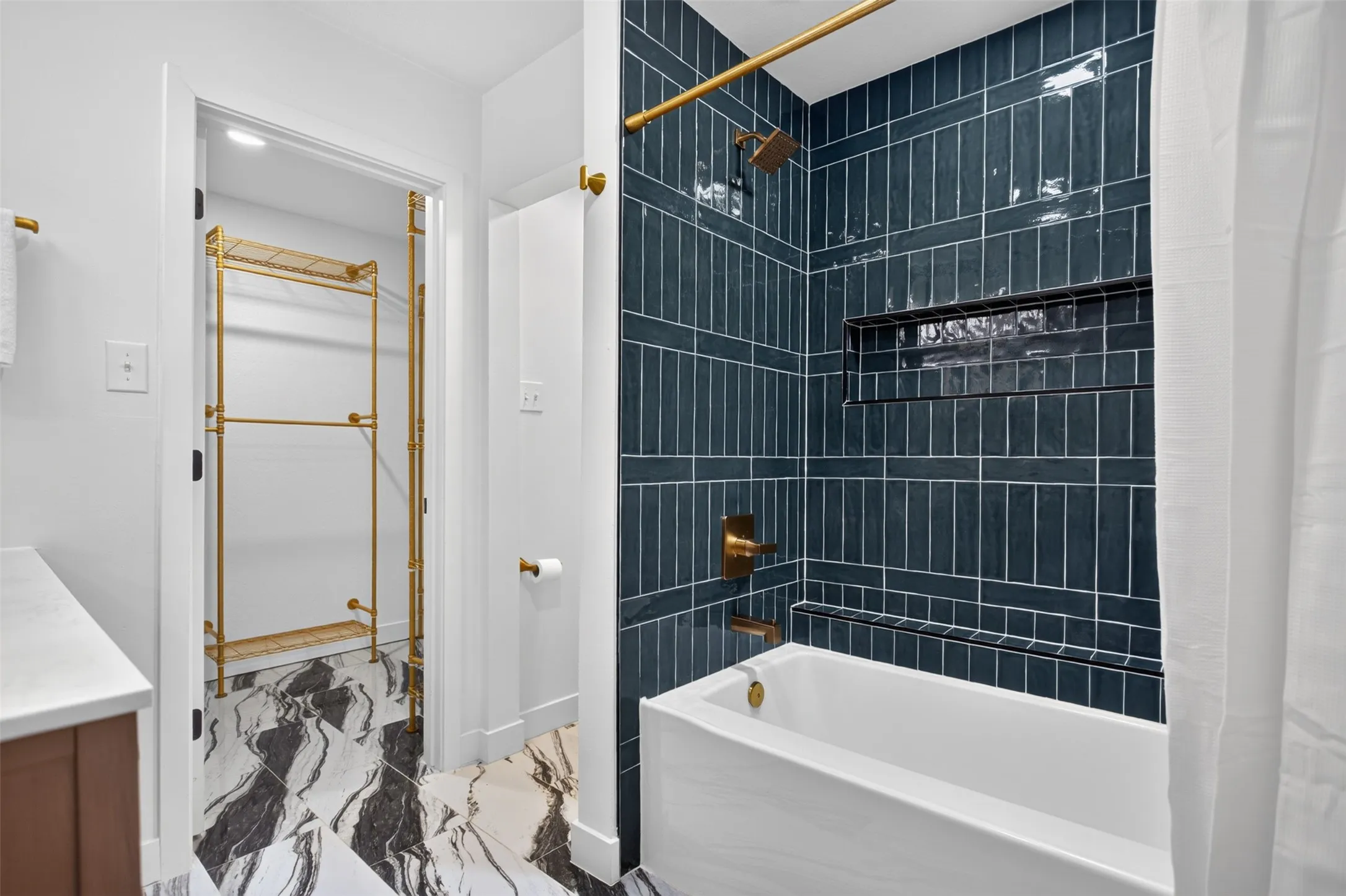 Bathroom featuring a deep soaking tub with a dark blue subway tile surround and a built-in shower niche attached custom closet