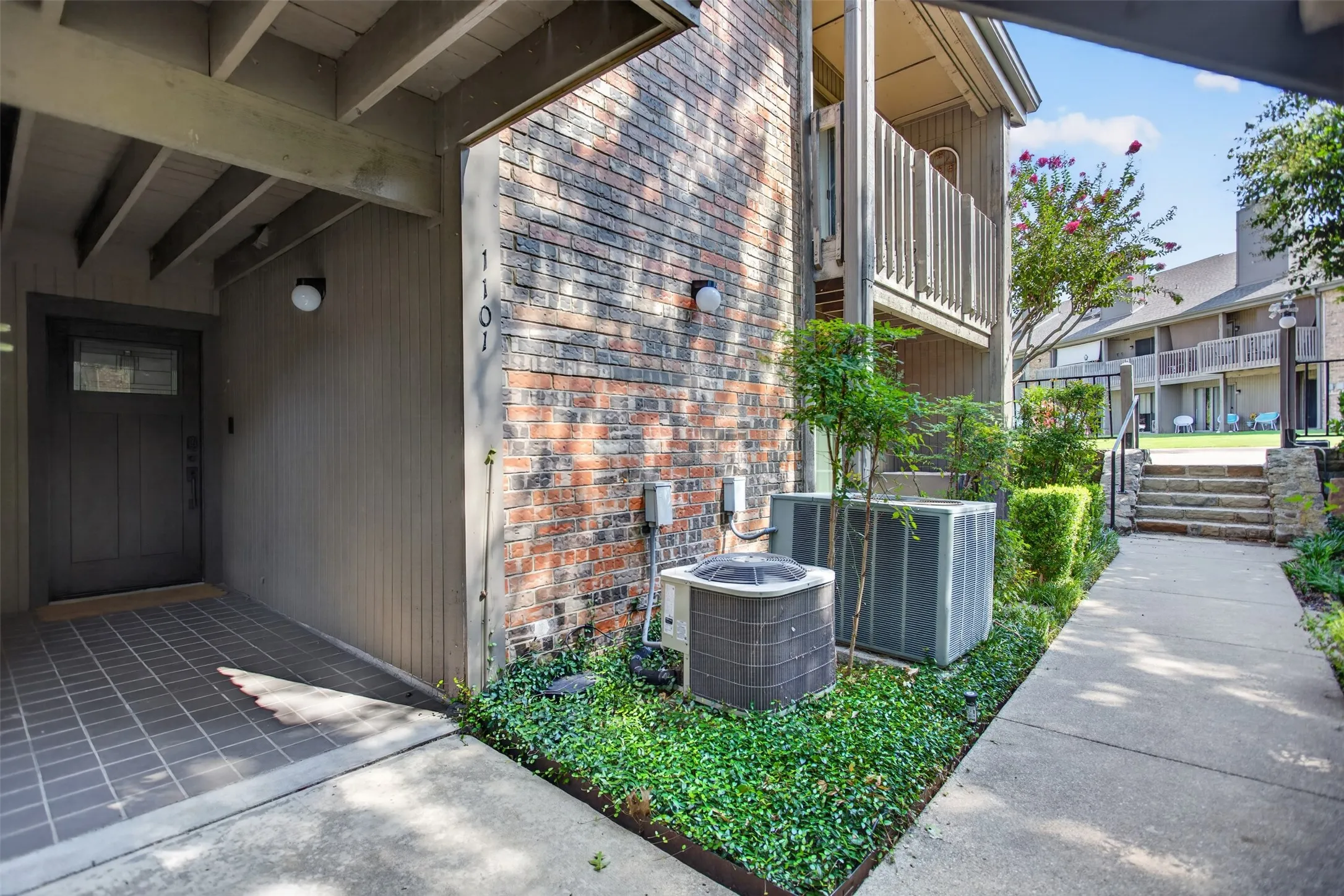 Entryway featuring a dark paneled door with glass insert, overhead lighting, and an adjacent brick facade