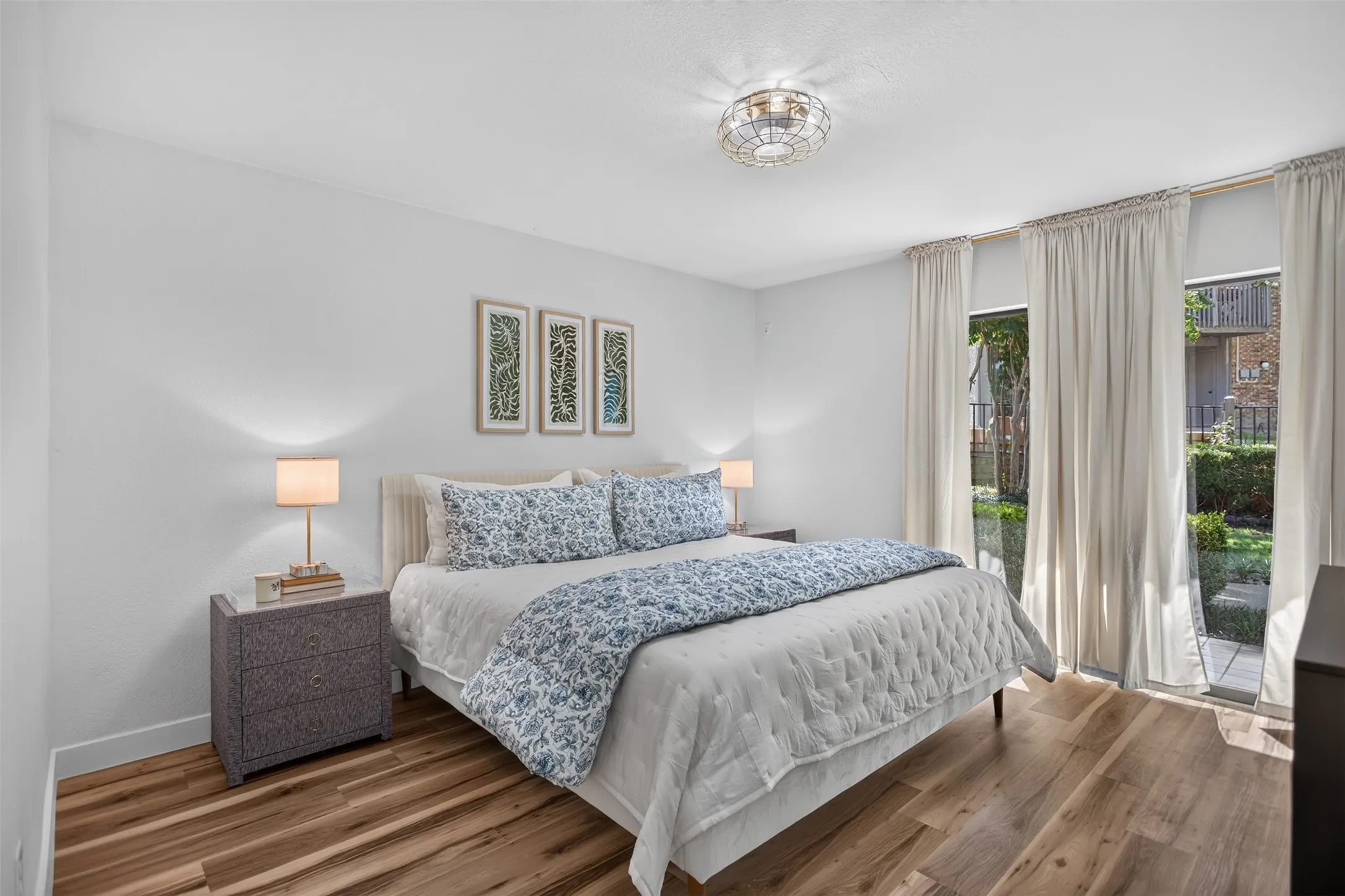Spacious room featuring wood-finish flooring, white walls, and a contemporary ceiling light fixture