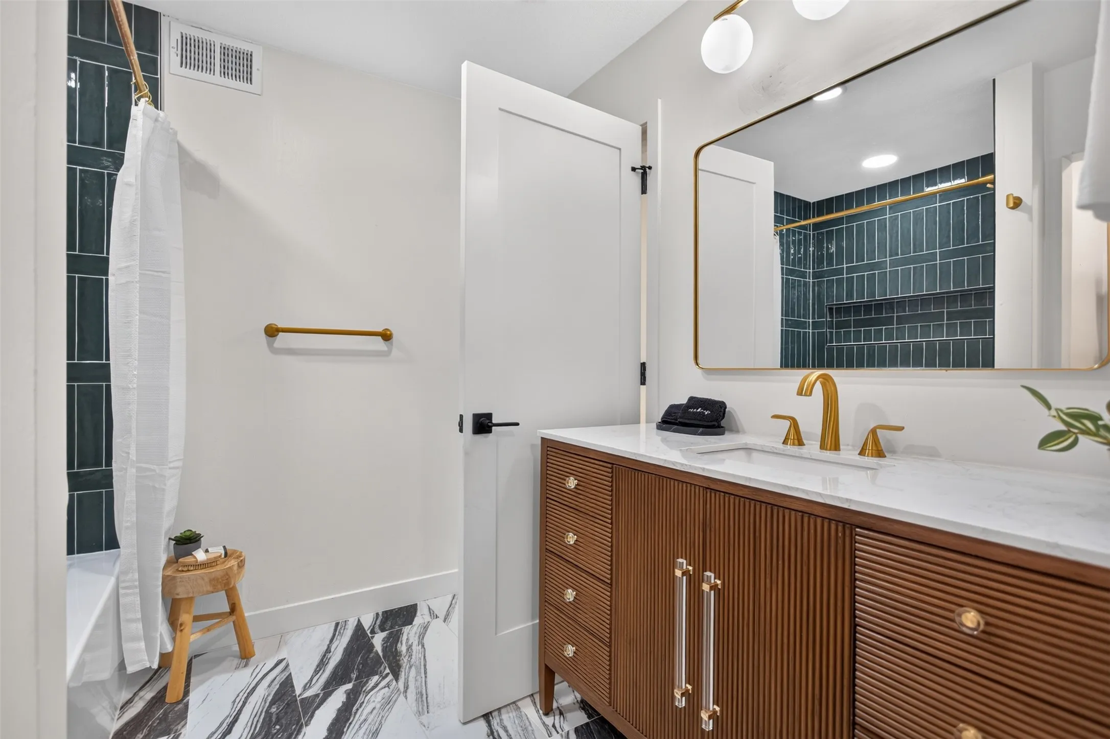 Bathroom featuring a wood-finish vanity with fluted details, a white countertop, and gold-tone fixtures