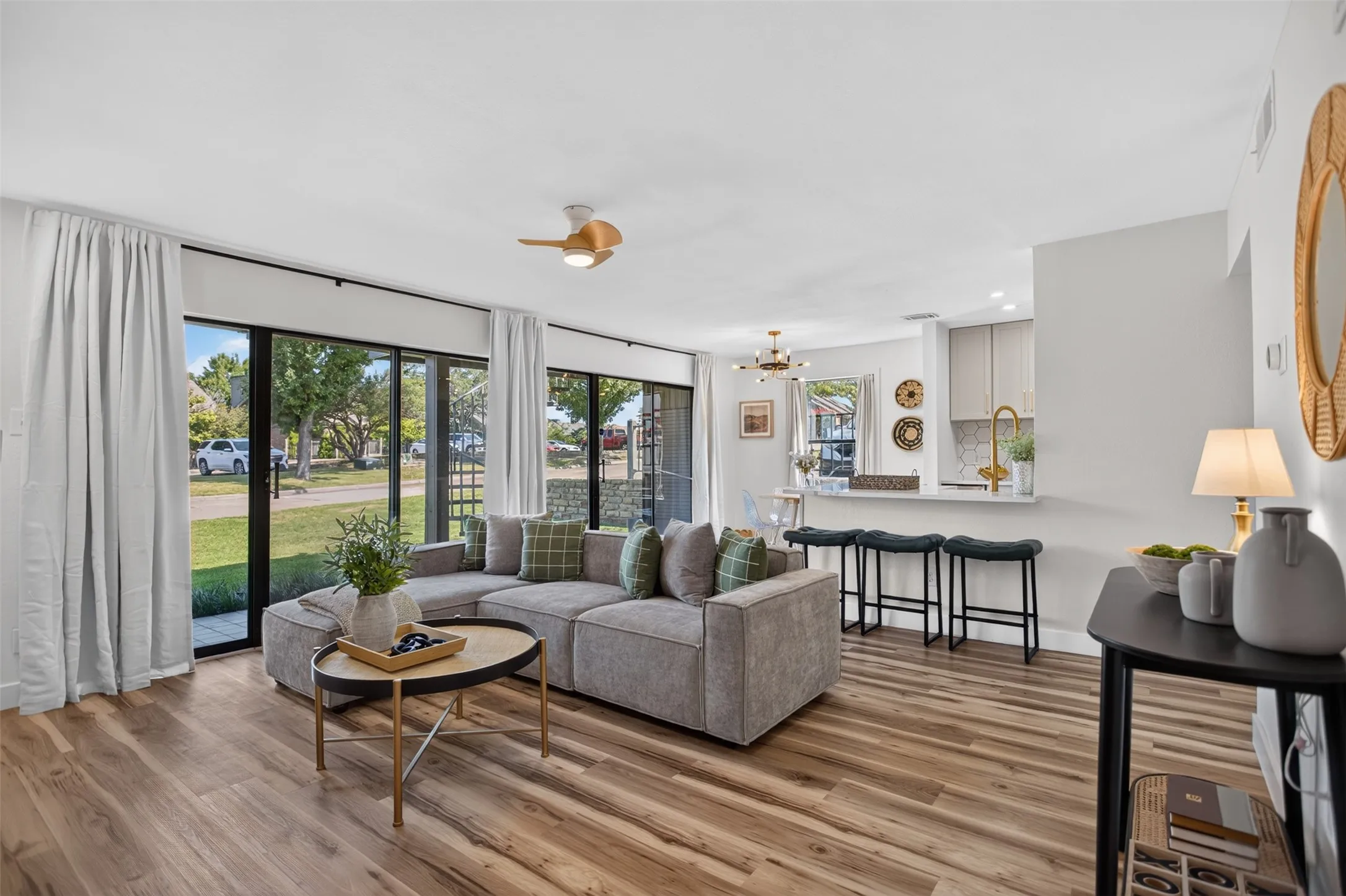 Open-concept living space featuring wood-finish flooring, a contemporary ceiling fan, and extensive sliding glass doors