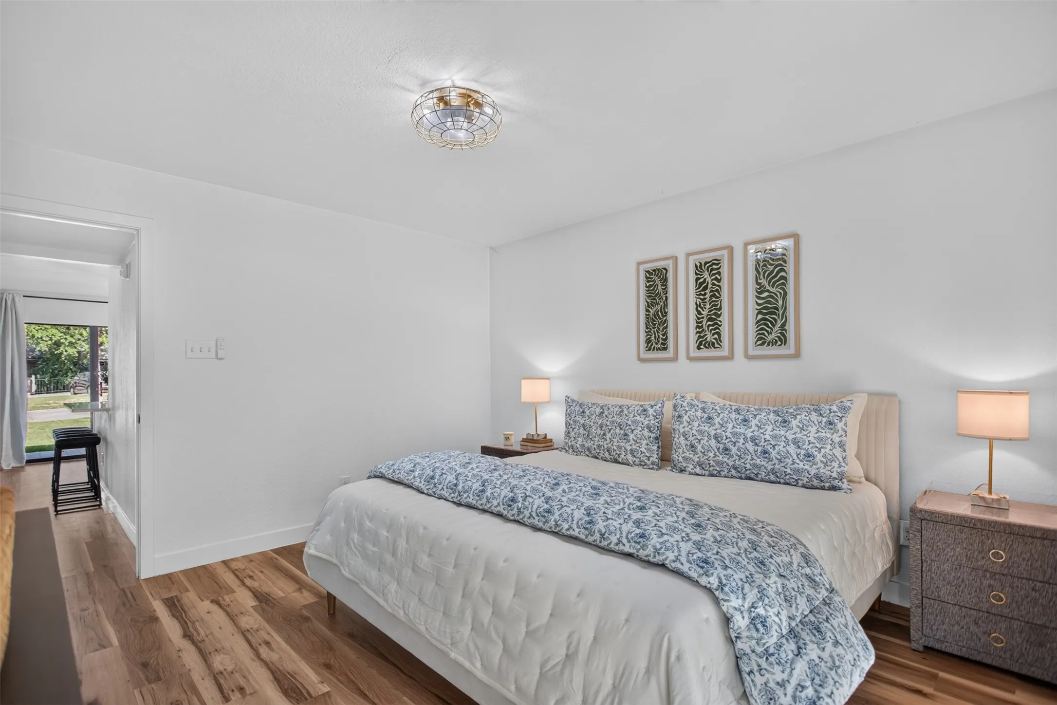 Bright bedroom featuring wood-finish flooring, crisp white walls, and a decorative ceiling light fixture