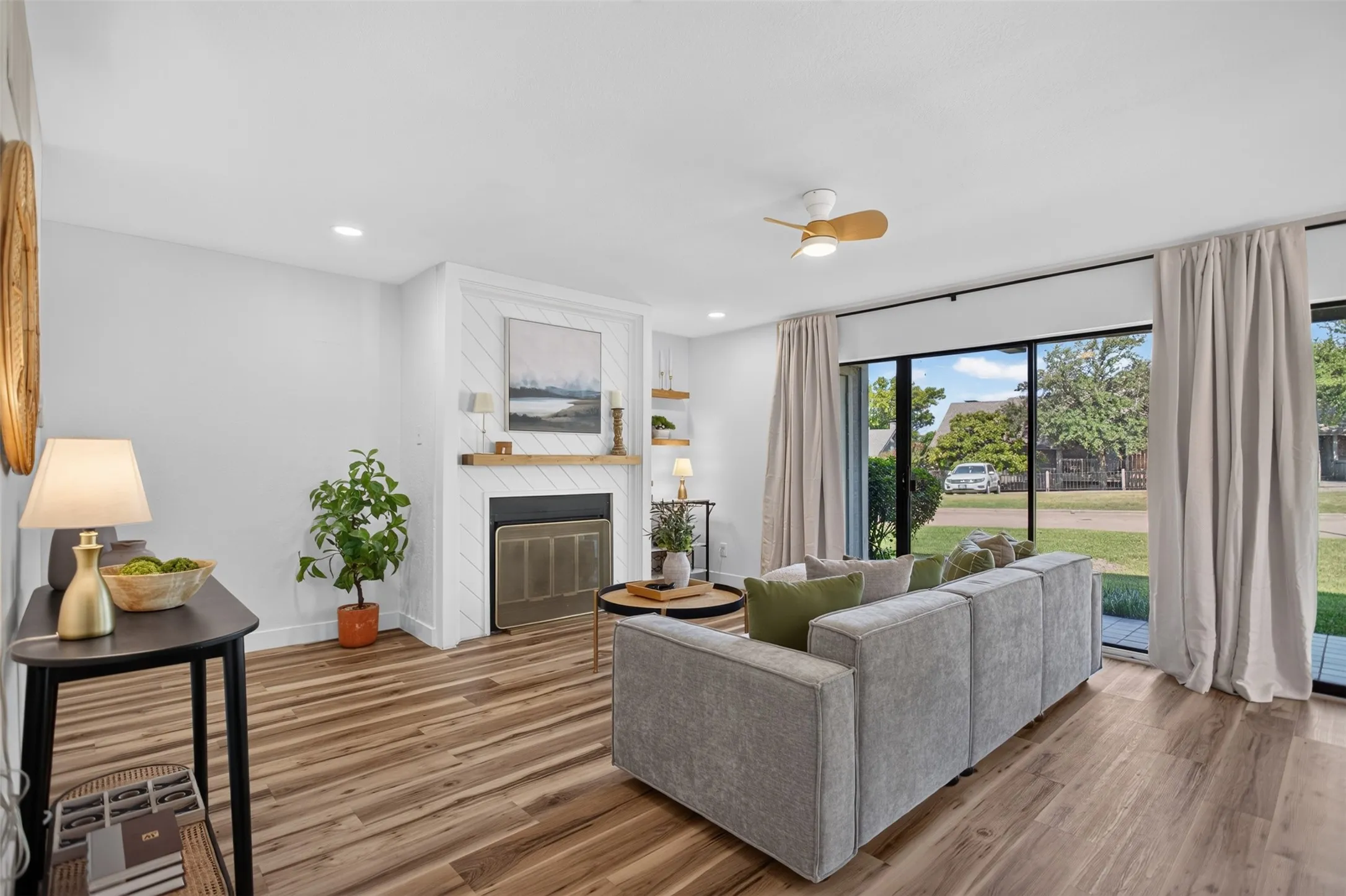 Living area featuring wood-finish flooring, a fireplace with a decorative mantel and shiplap surround, and recessed lighting