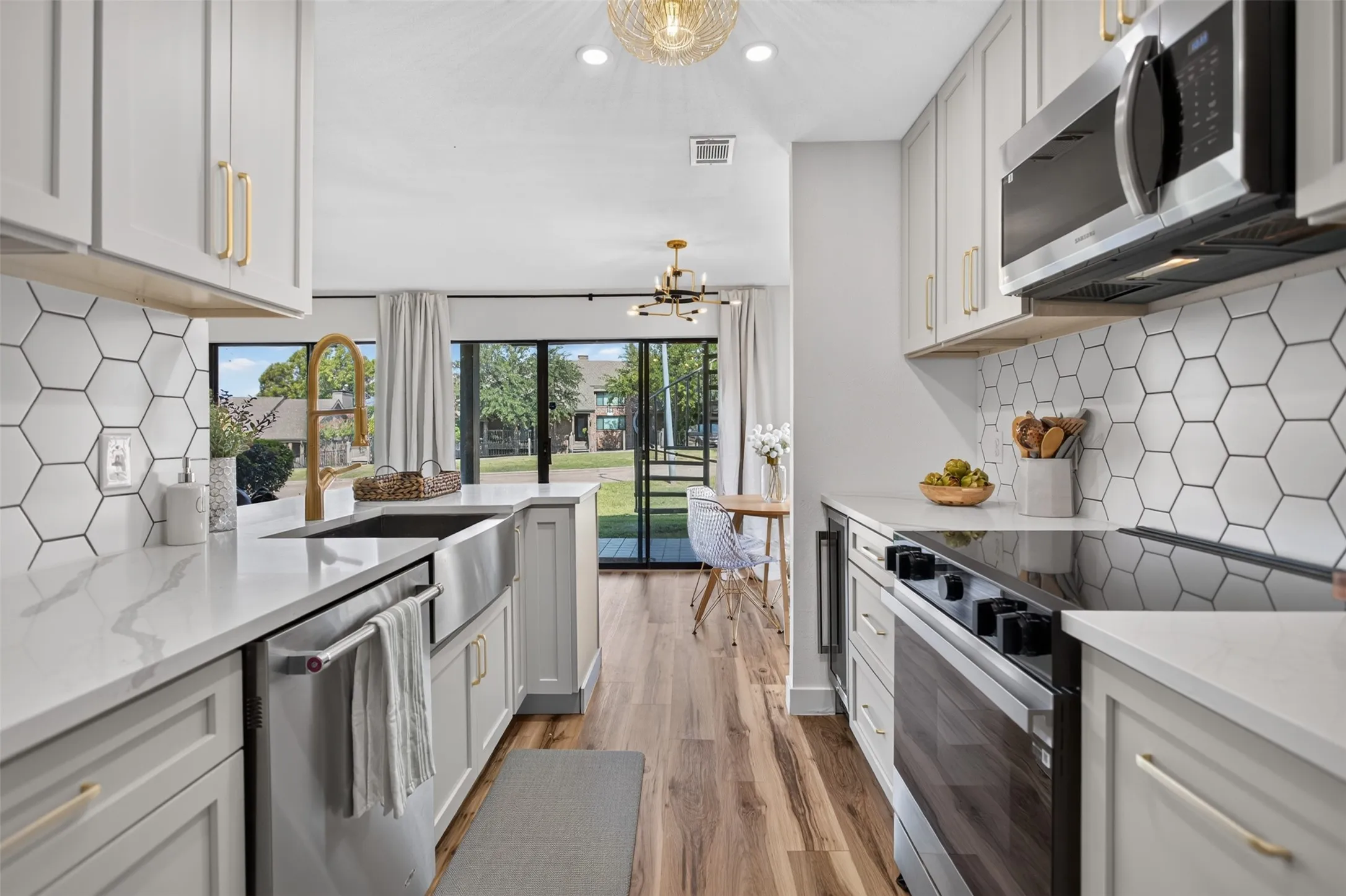 Kitchen featuring white shaker cabinetry with gold-tone hardware, white hexagon tile backsplash, and wood-finish flooring