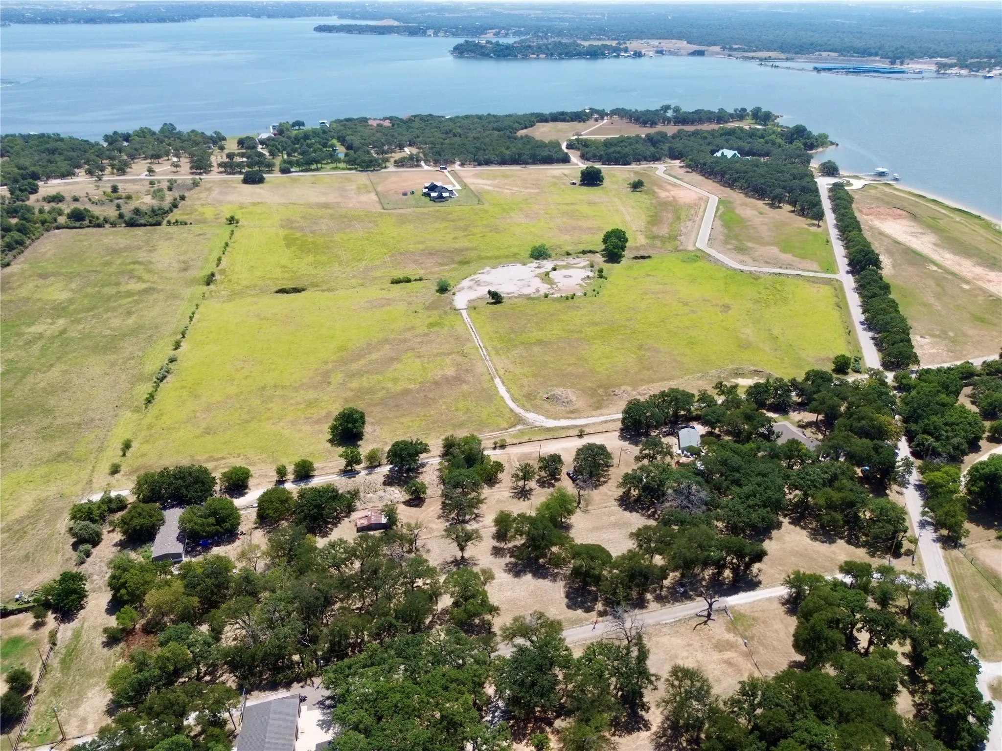 Expansive property featuring waterfront access, multiple open fields, paved roads, and mature tree coverage