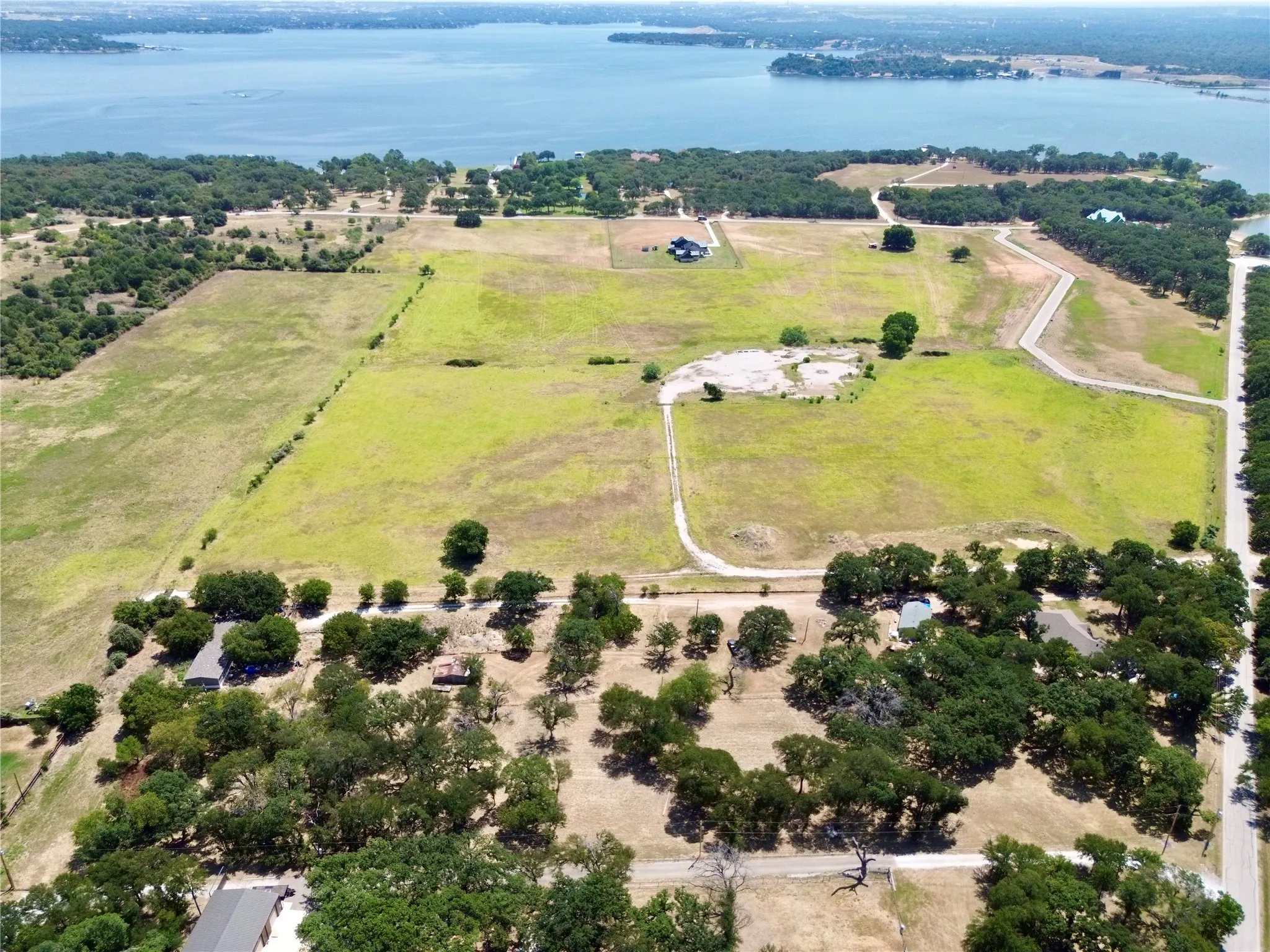 Expansive acreage featuring a substantial body of water, scattered mature trees, and a visible road network